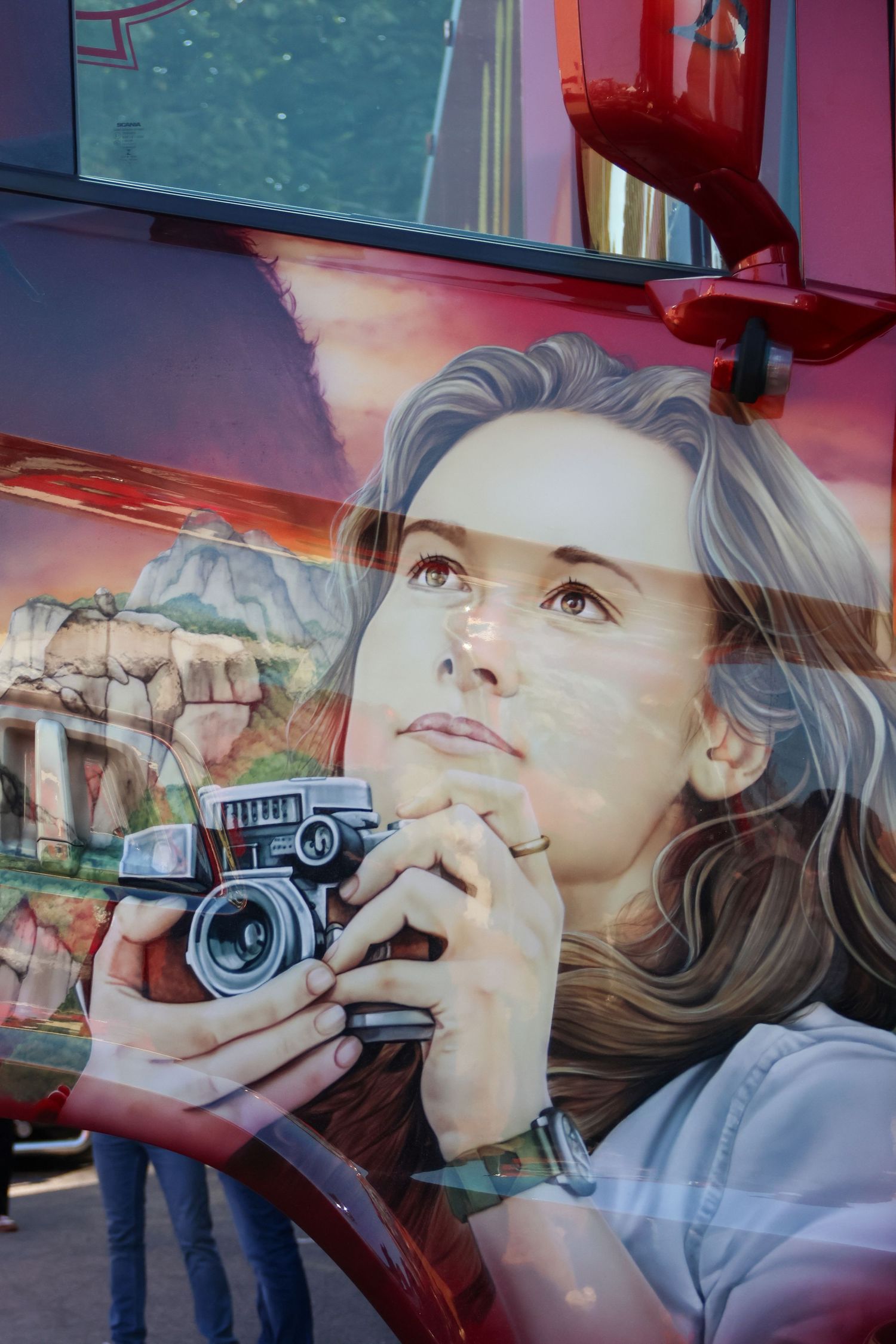 Detailed airbrush painting of a woman holding a vintage camera on a red truck.