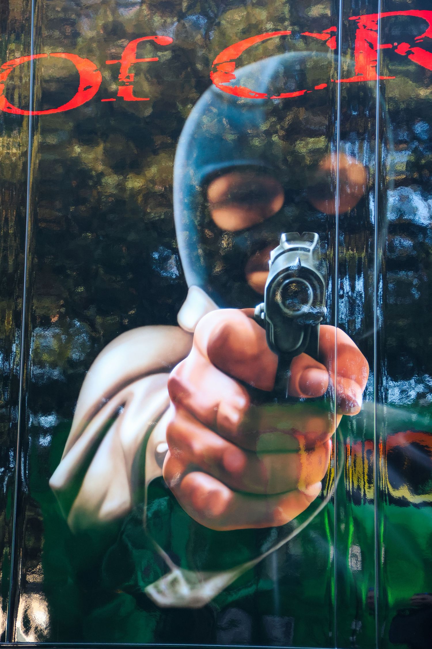 Dramatic airbrush mural of a masked figure pointing a gun directly at the viewer.
