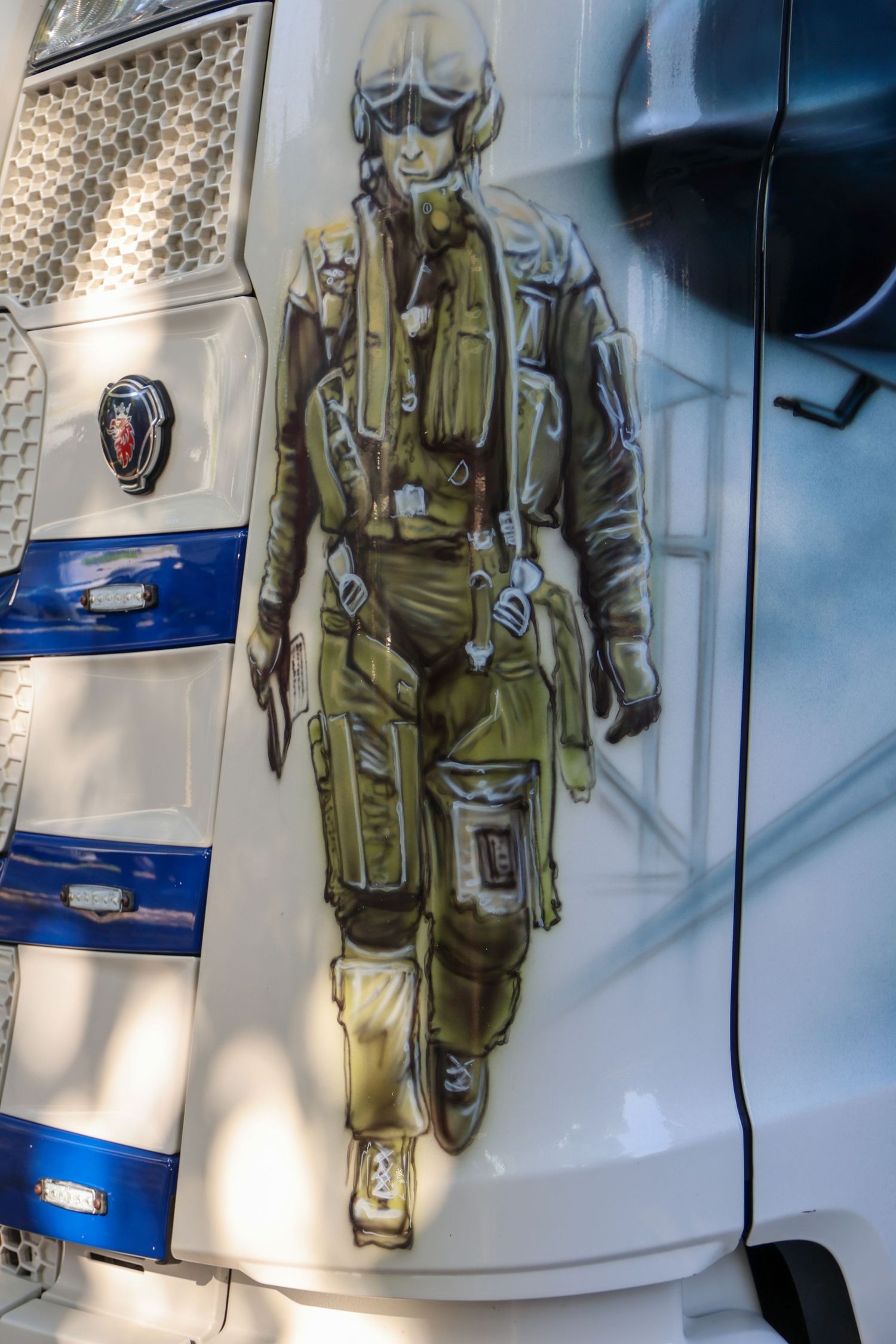 Detailed airbrush painting of a WWII fighter pilot in full gear on the side of a white Scania truck.