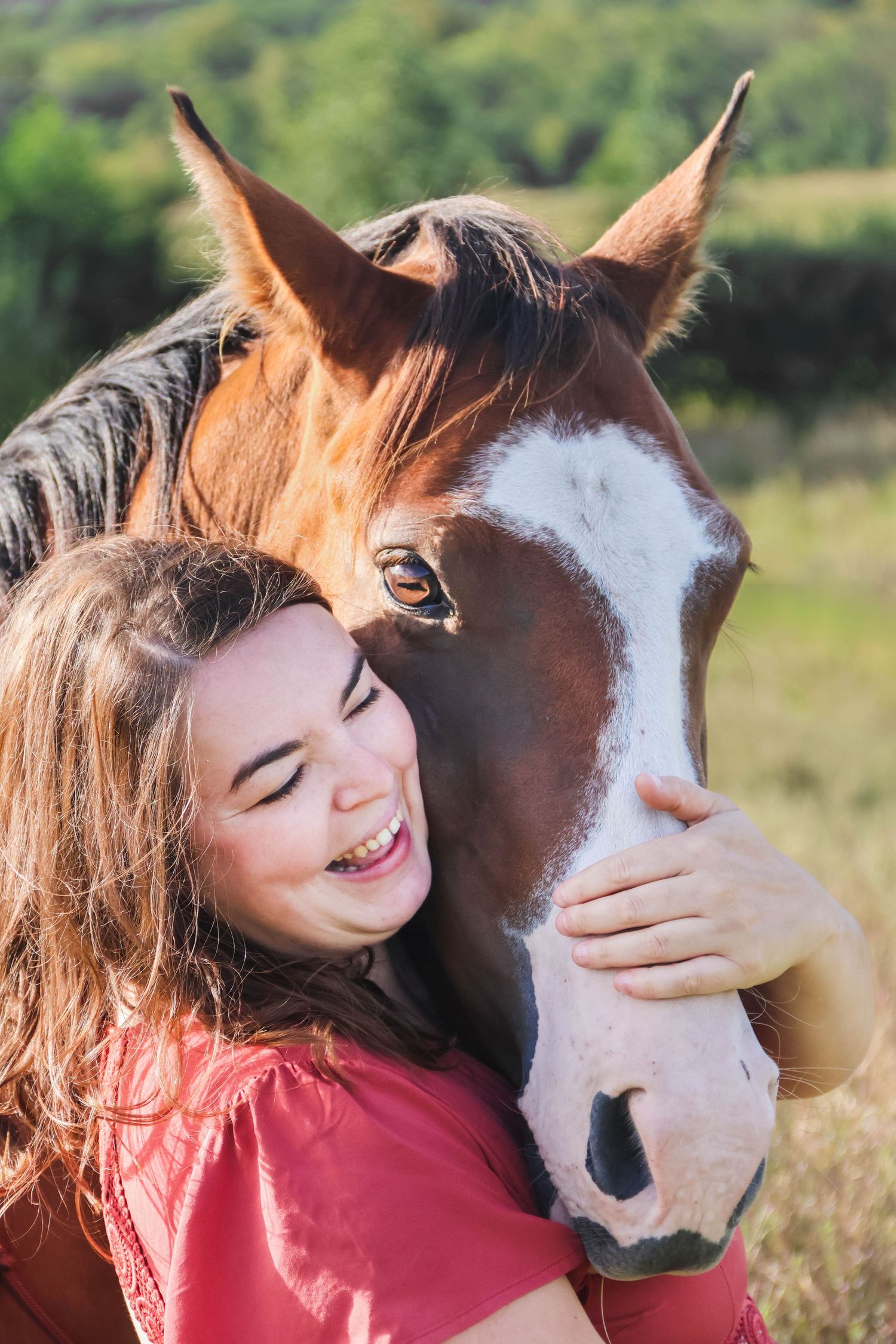 Séance animaux lifestyle — jeune fille riant en serrant le museau de son cheval alezan dans la lumière dorée, photographe Épernay Marne.