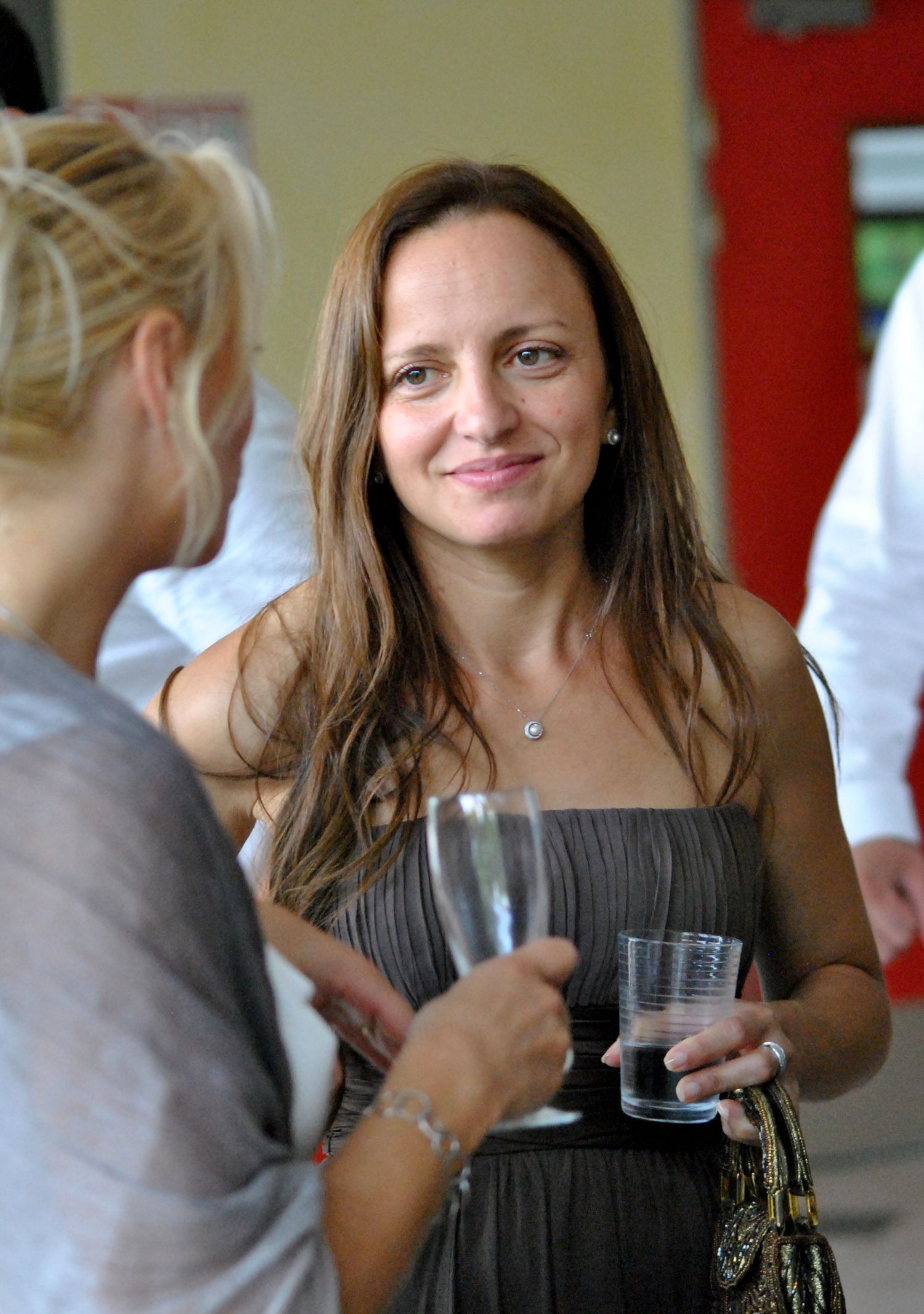 Elegant woman in gray dress holds champagne glass at a social gathering.
