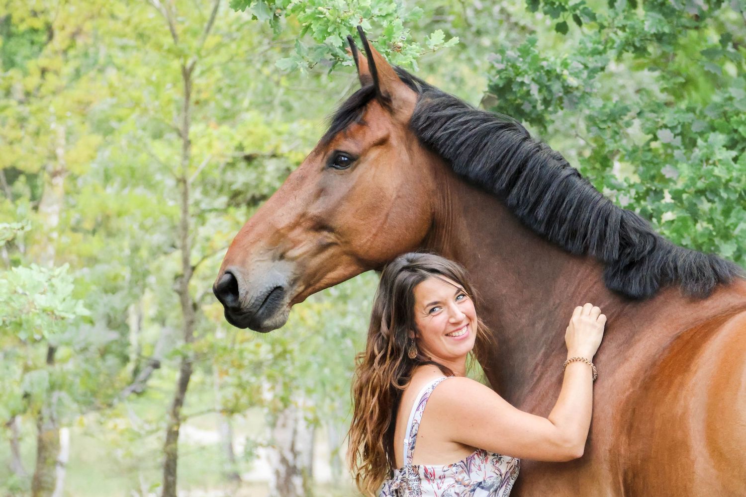 Séance lifestyle — jeune femme en robe fleurie face à son cheval brun dans les bruyères, photographe Aisne Guignicourt.