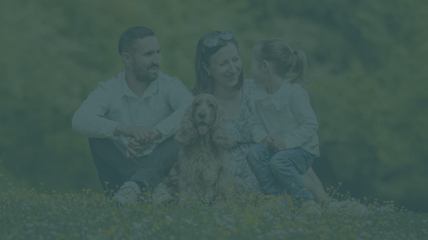 Happy family with parents and child sitting on grass outdoors with their golden cocker spaniel dog.