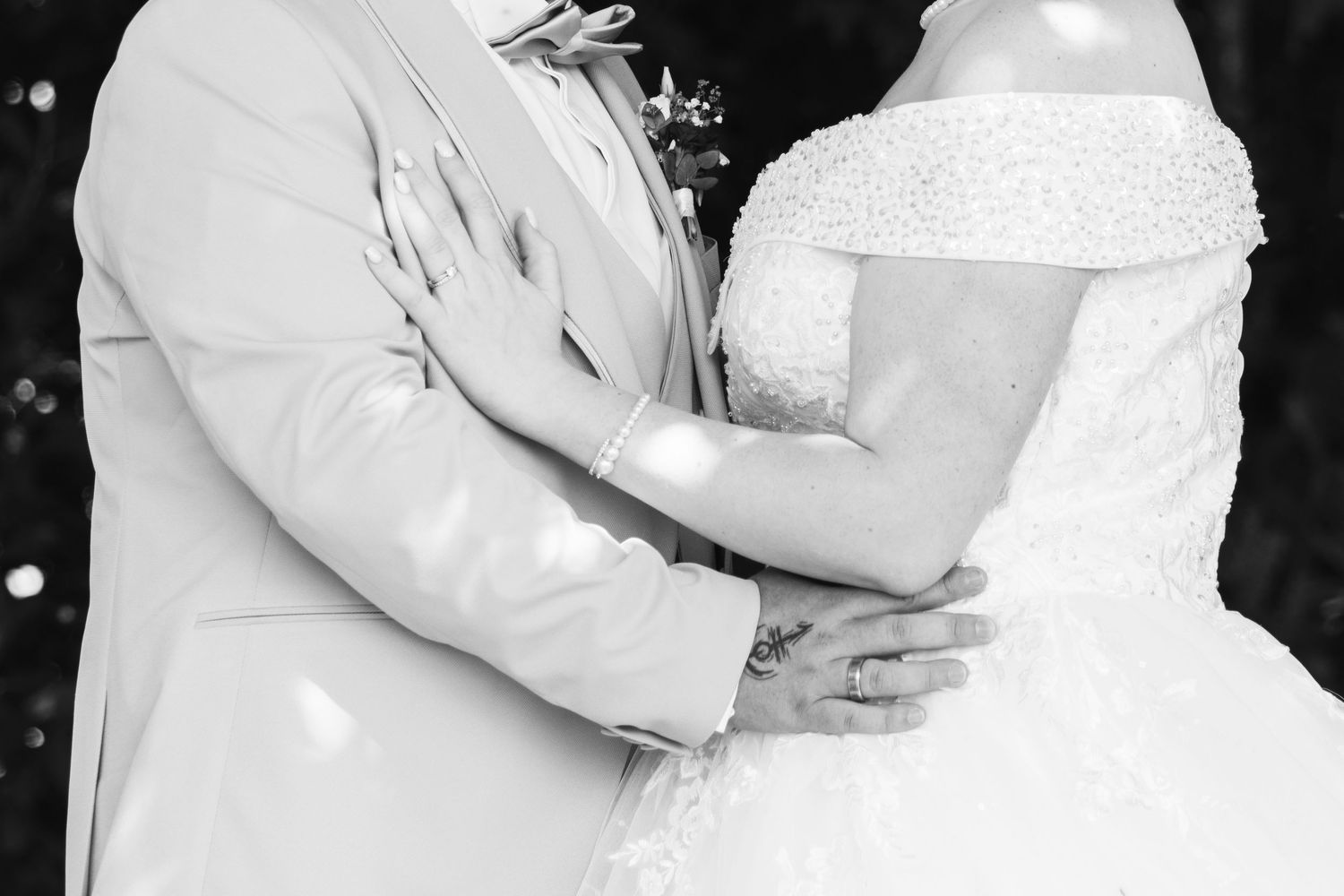 Black and white photo of a bride and groom embracing at their wedding ceremony.