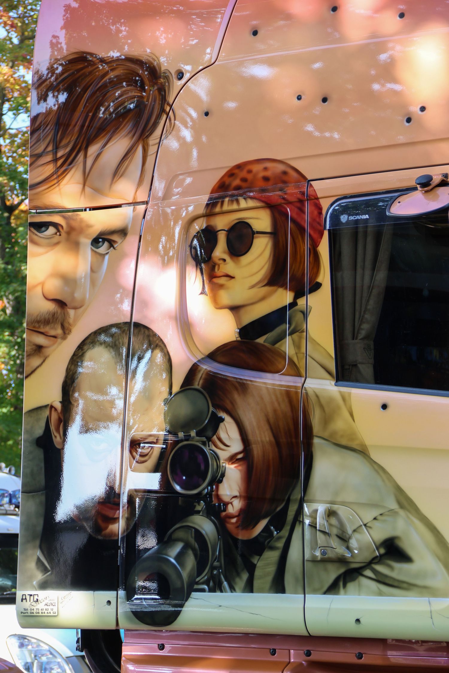 Artistic airbrush mural on a truck featuring three stylized figures including a woman with sunglasses and camera.