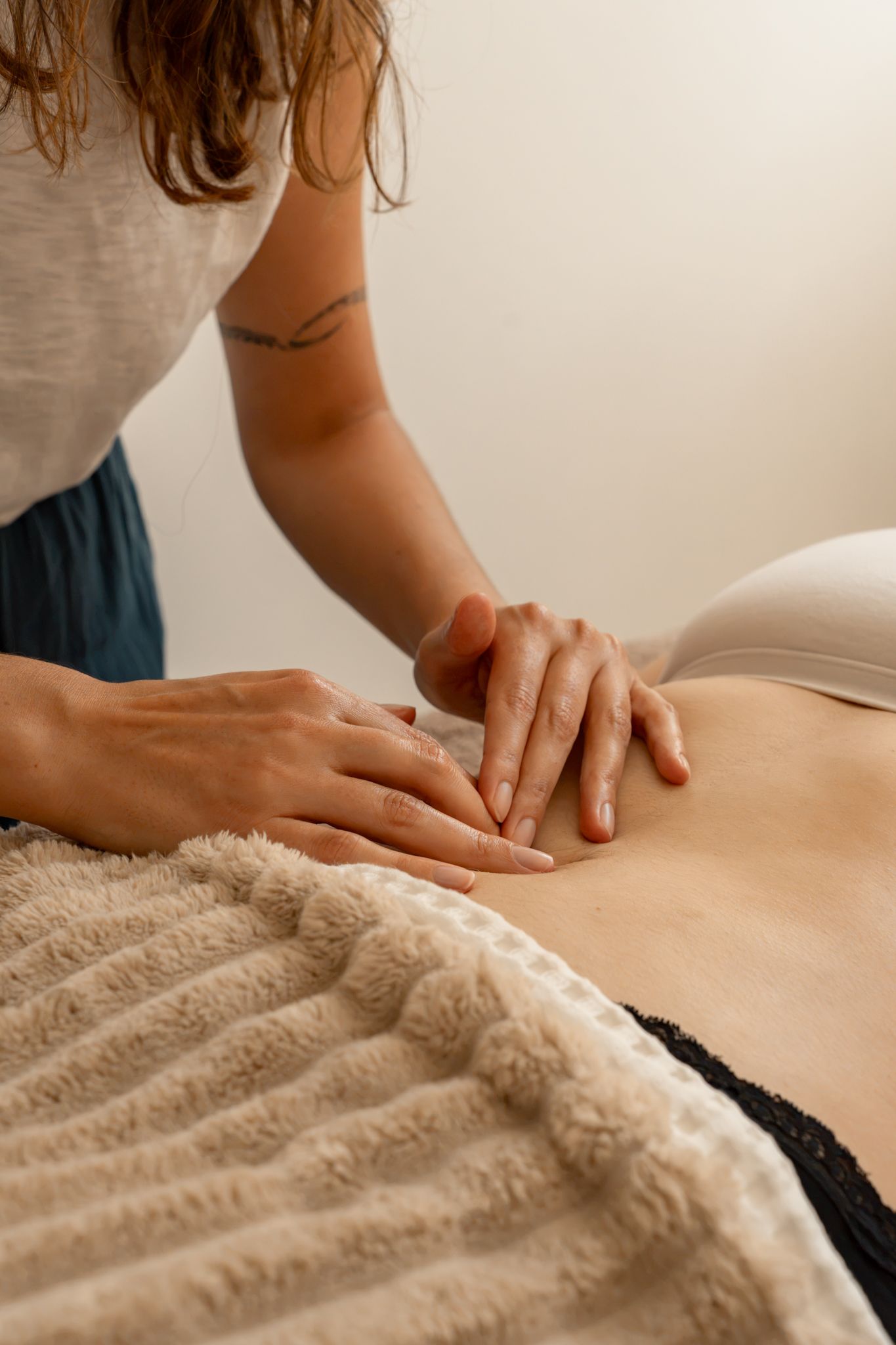 Massage therapist applying deep tissue back massage technique on client lying on treatment table.