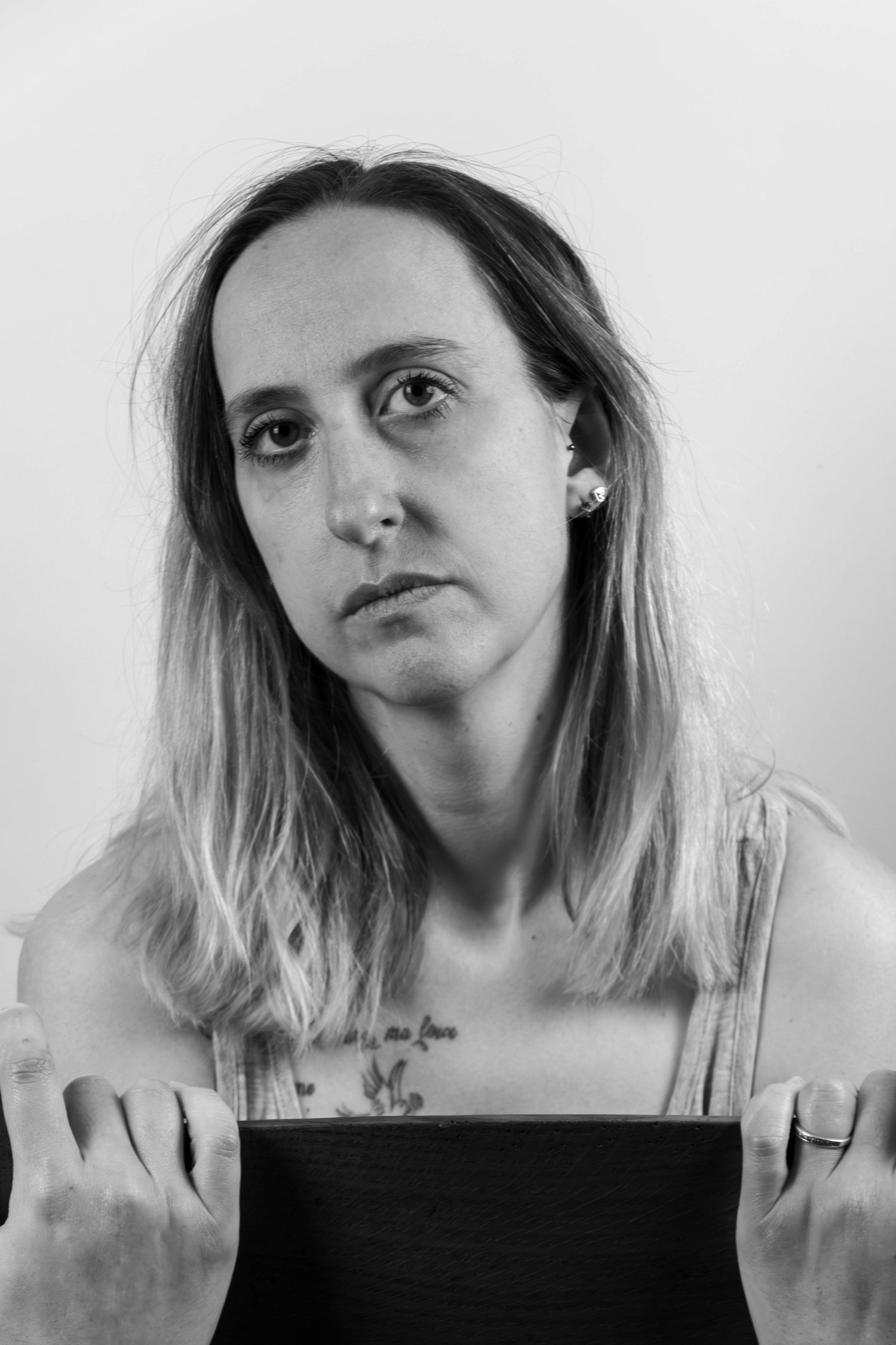 Séance Harmonie — portrait studio noir et blanc femme tatouée retenant ses cheveux en débardeur et bracelets, photographe Rethel Ardennes.