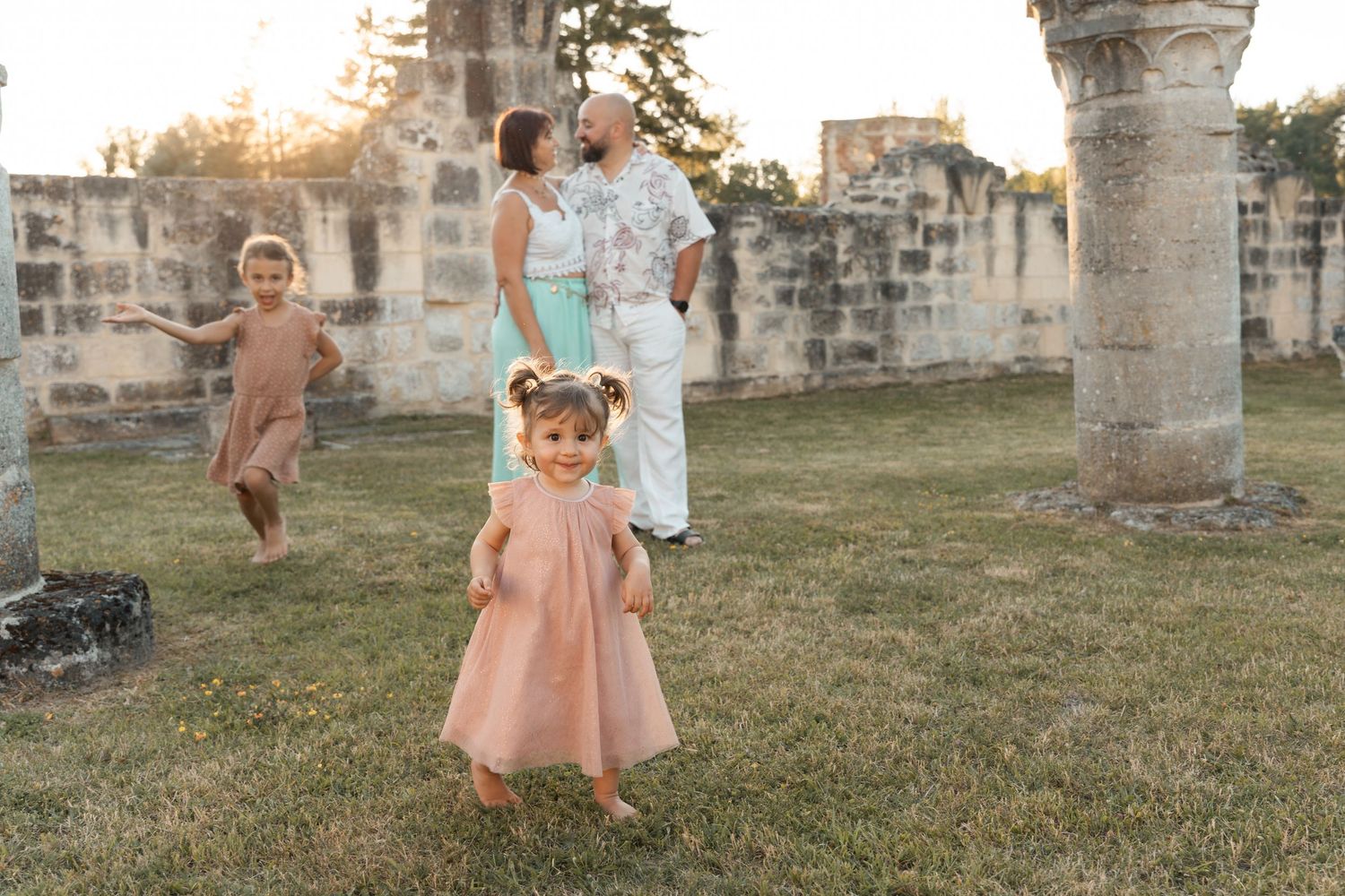 Young family with two children playing among ancient stone ruins during a golden hour photo session.