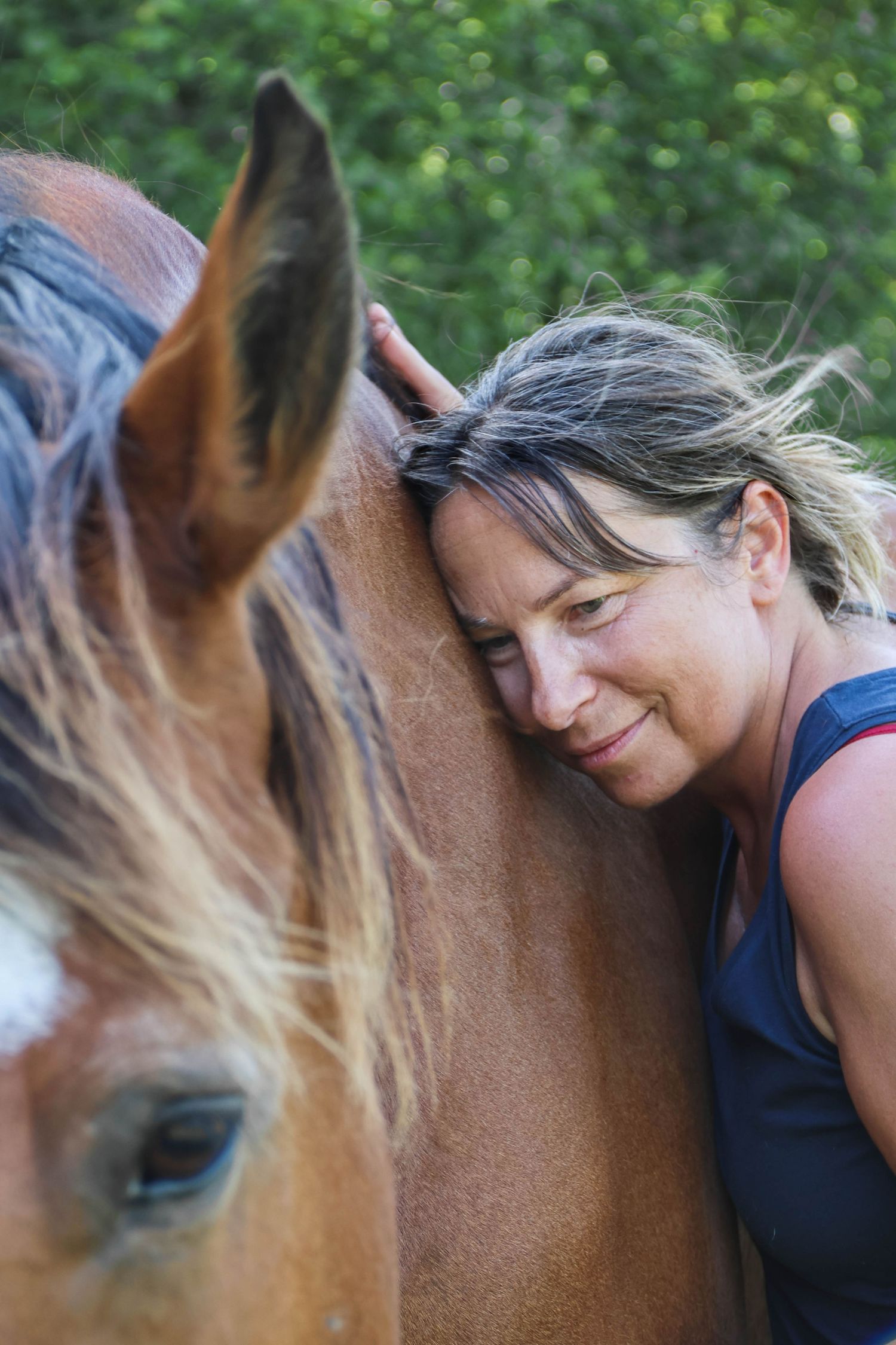 Séance cheval lifestyle — femme souriante tête posée contre son cheval alezan dans un cadre naturel paisible, photographe Guignicourt Aisne.