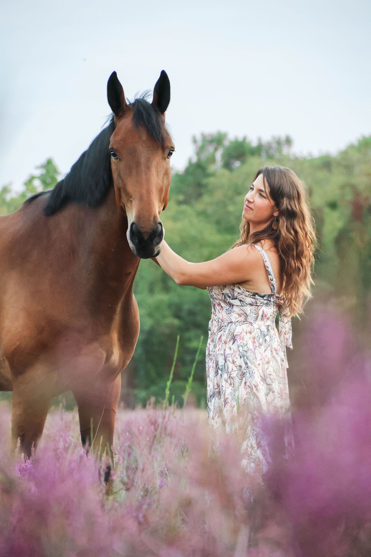 Séance lifestyle — jeune femme en robe fleurie face à son cheval brun dans les bruyères, photographe Aisne Guignicourt.