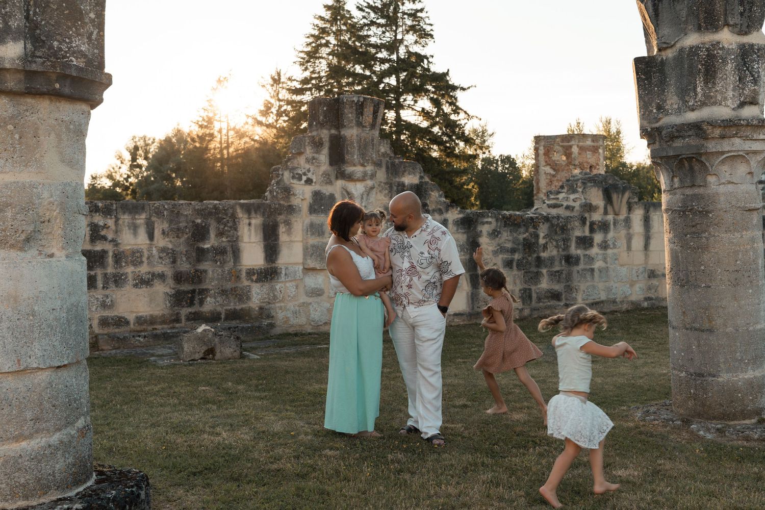 Family with children enjoys a sunset moment among ancient stone ruins in a lush setting.