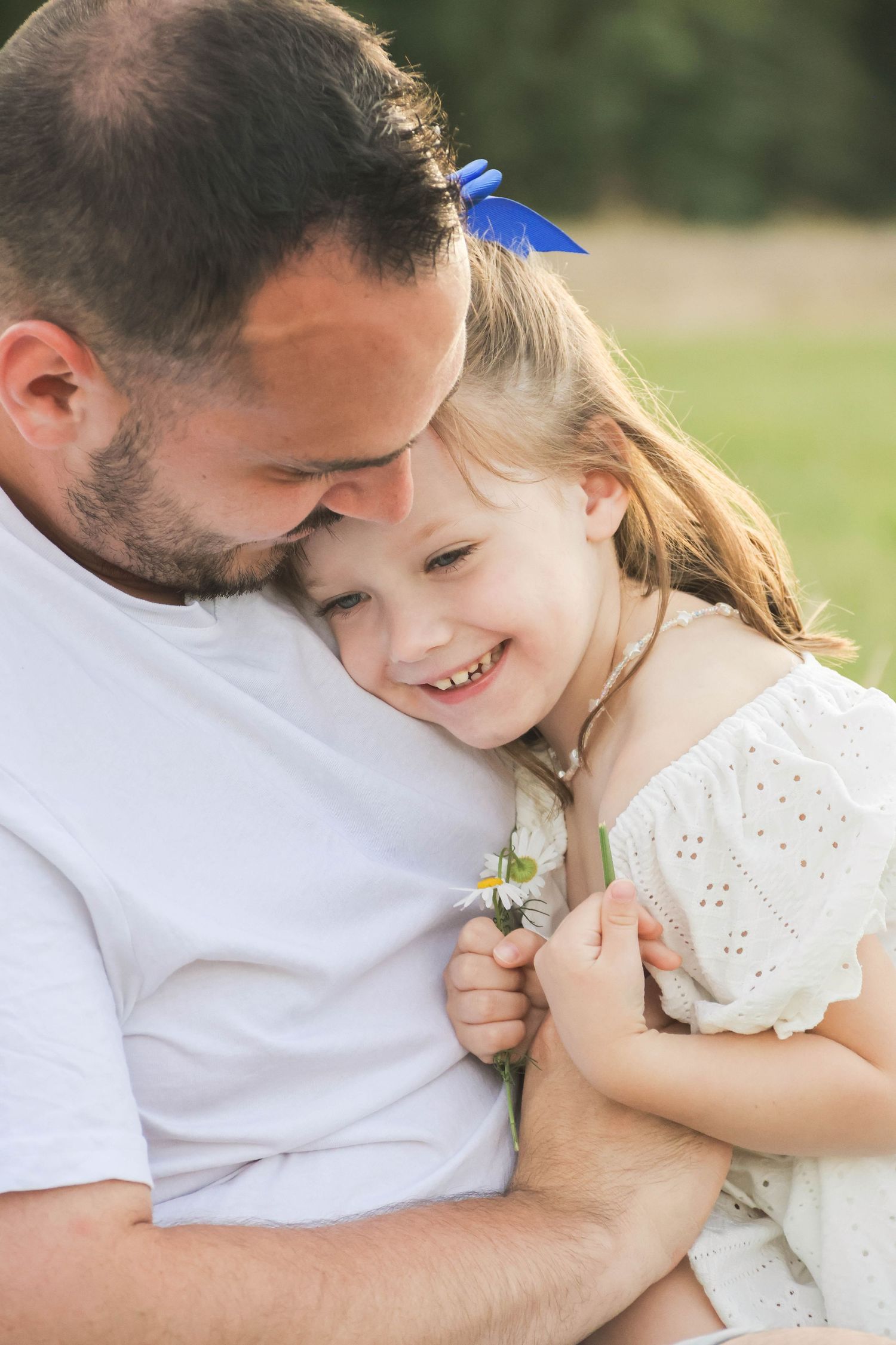 Séance famille lifestyle — petite fille riant blottie contre son papa en extérieur ensoleillé, photographe famille Laon Aisne.