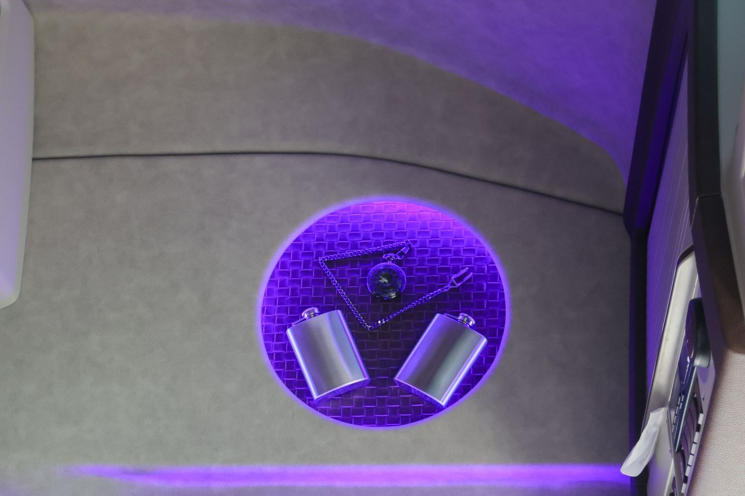 Purple LED lit circular speaker enclosure with two chrome tweeters inside a vehicle.