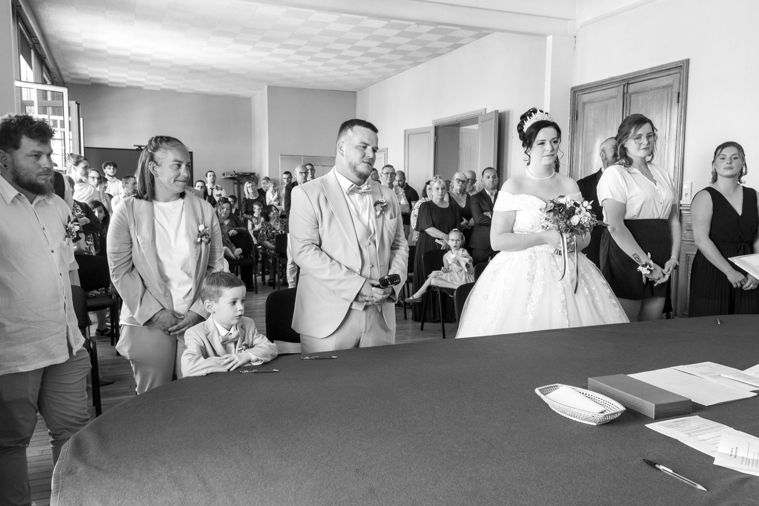Black and white photo of a bride and groom standing at the altar during their wedding ceremony indoors.