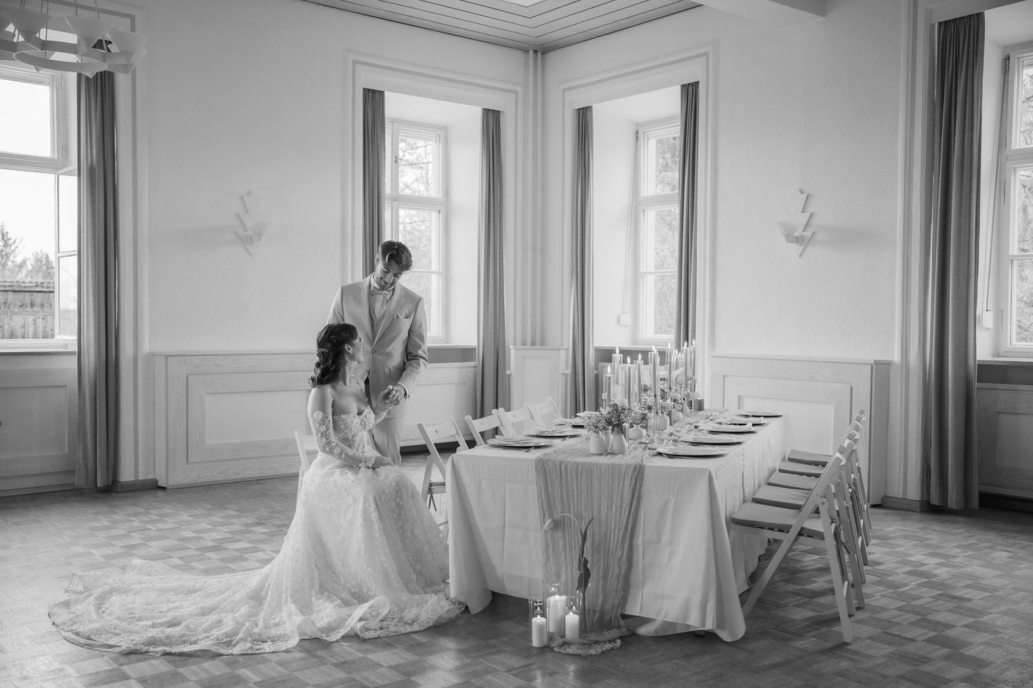 Elegant interior space with large windows, intricate molding and polished floors in black and white photography.