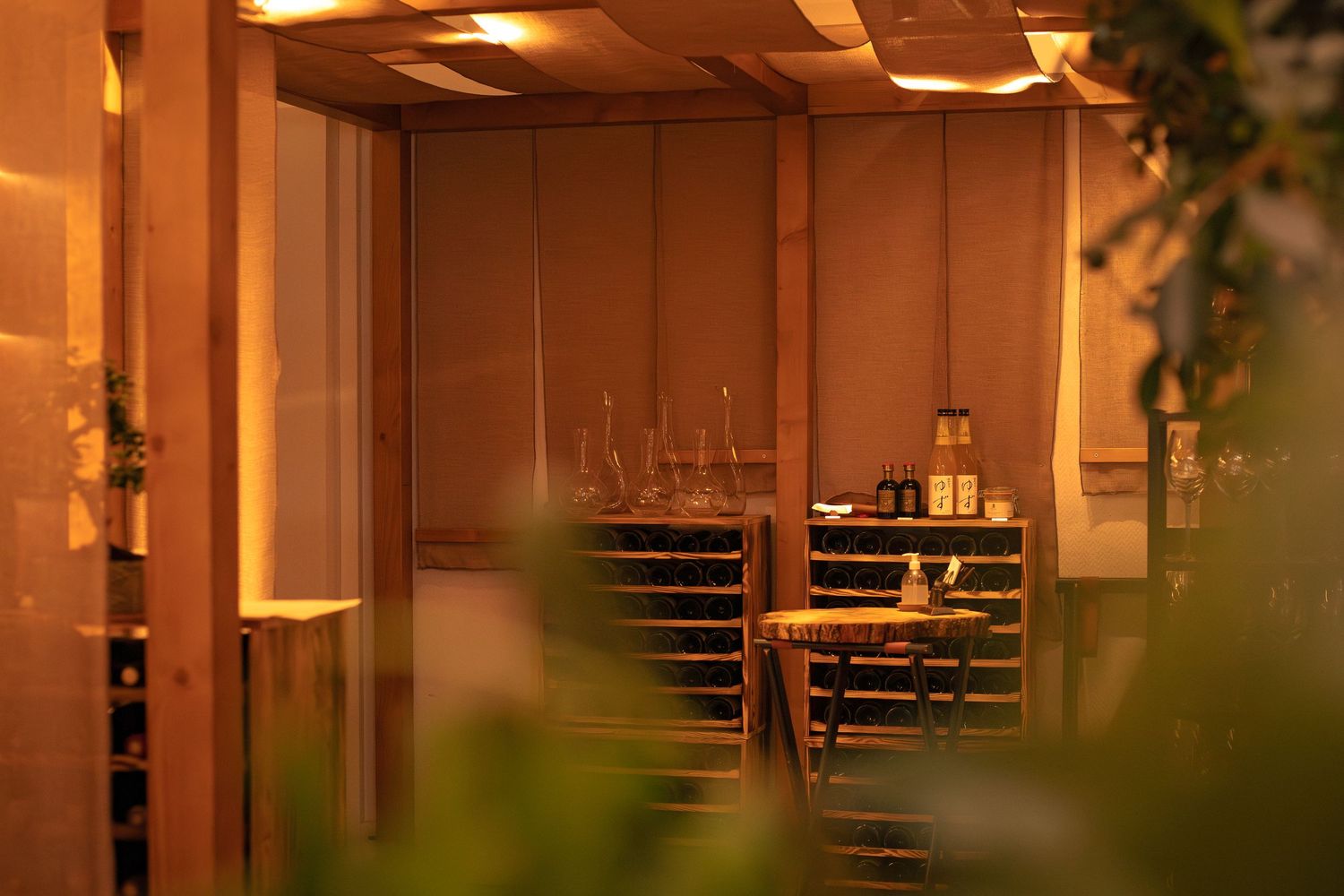 Intérieur de restaurant faiblement éclairé avec tables et chaises visibles à travers des éléments flous au premier plan.