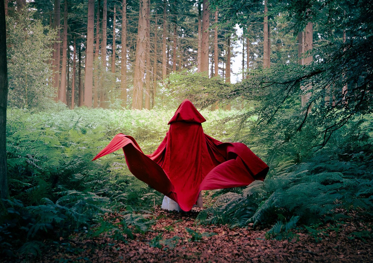 Une silhouette vêtue de rouge se déplace mystérieusement dans une forêt brumeuse, créant une scène éthérée