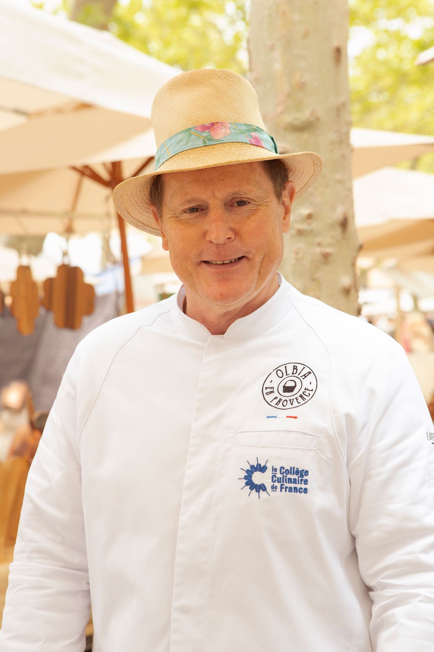 Des chefs en uniformes blancs et chapeaux travaillant lors d'un événement culinaire en plein air.