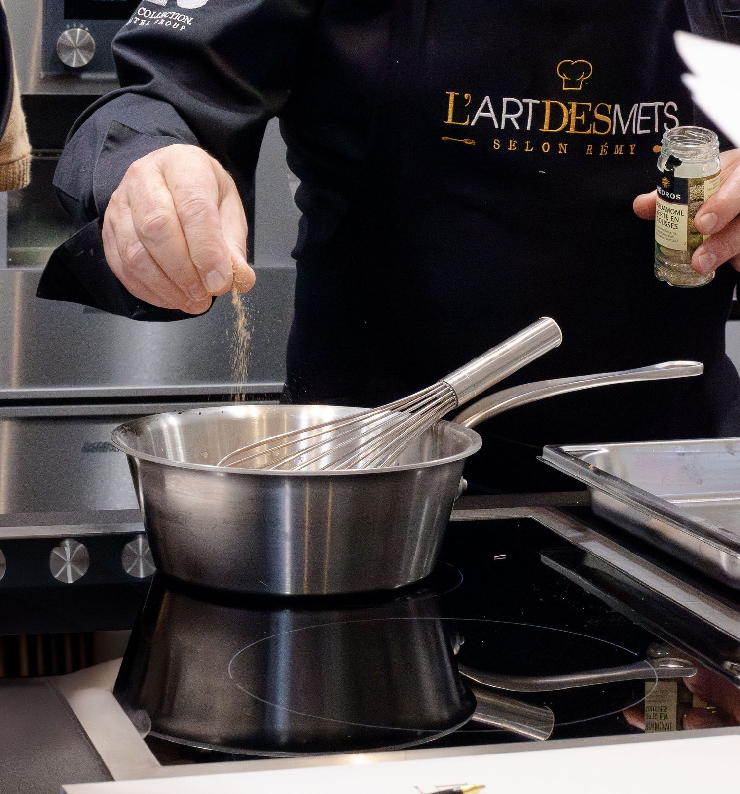 Chef professionnel cuisinant dans une cuisine de restaurant avec des casseroles et du matériel en acier inoxydable.