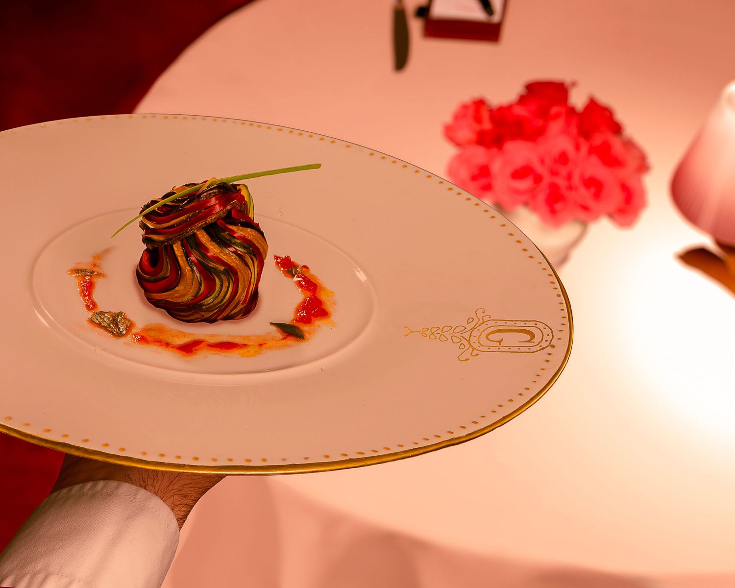 Assiettes raffinées avec présentation artistique des aliments et garniture rouge.