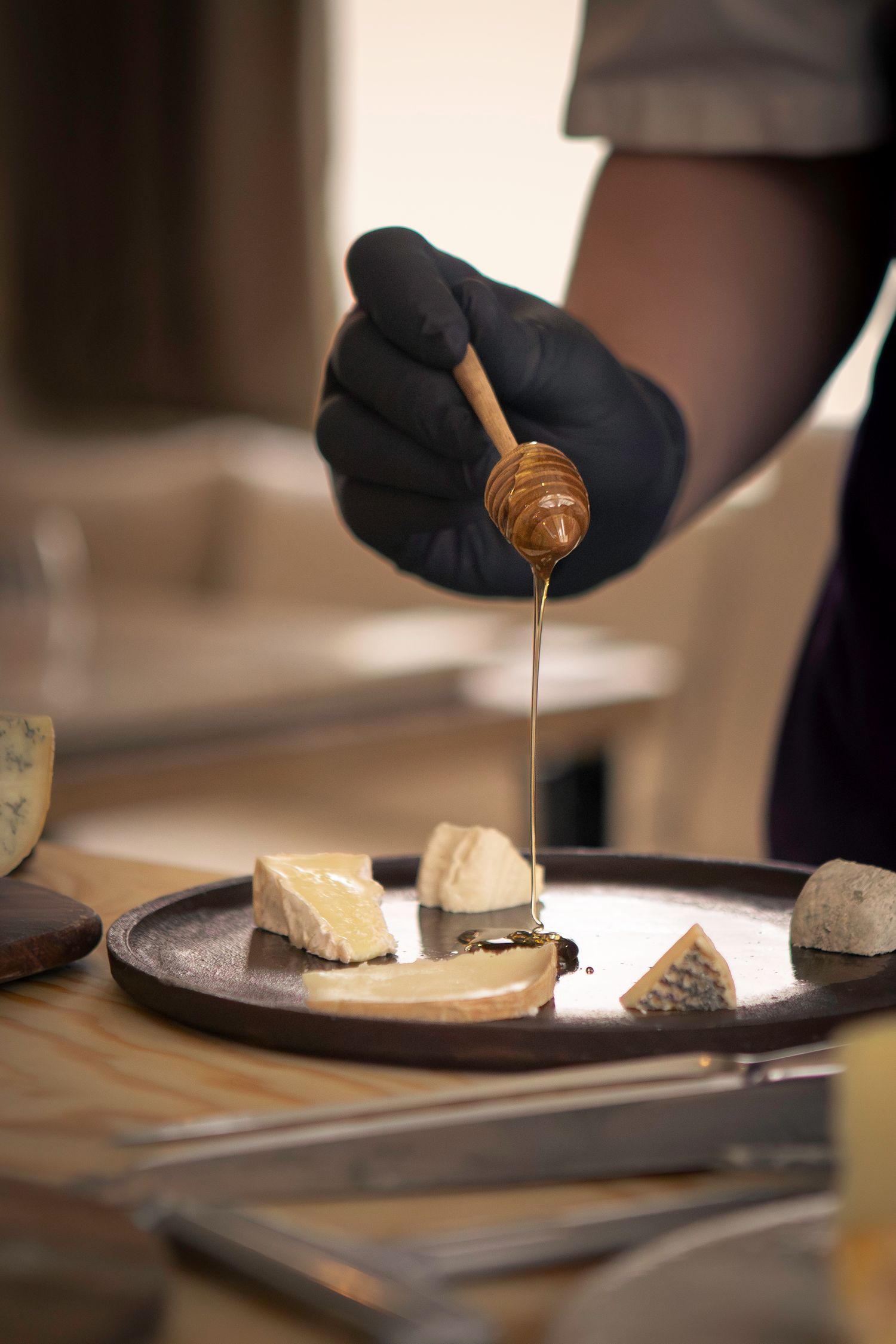 Close-up d'une main servant du miel sur une assiette de fromages