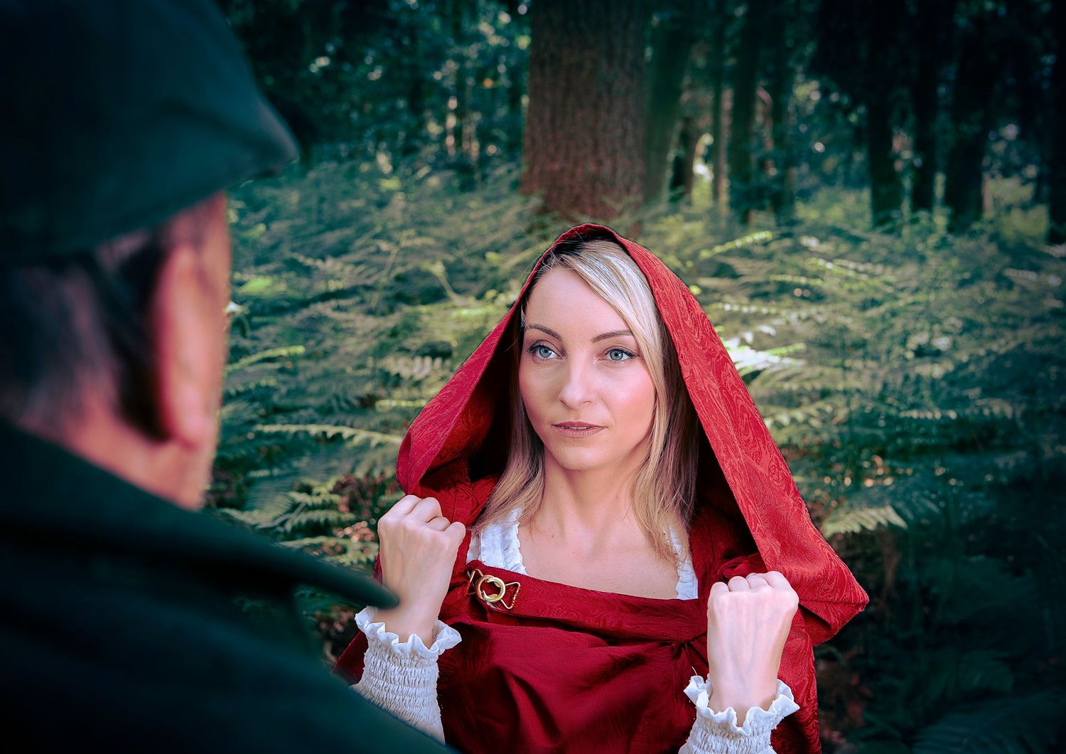 Portrait inspiré d'un conte de fées dans un décor forestier avec une cape à capuche rouge.