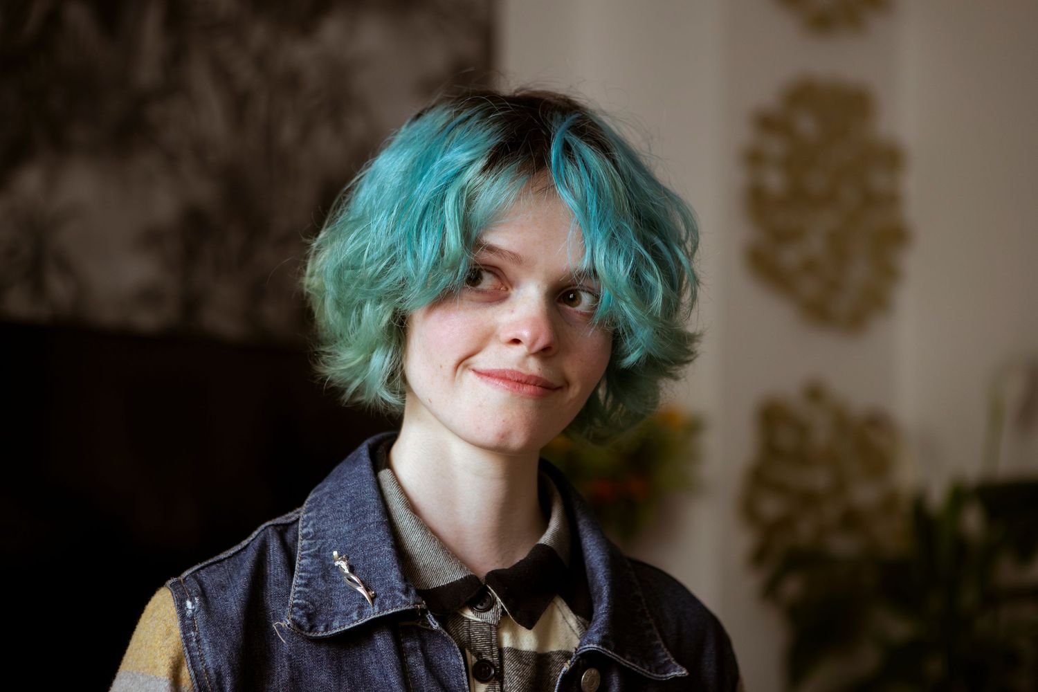 Portrait de mode avec une coiffure turquoise vibrante sur un fond neutre.