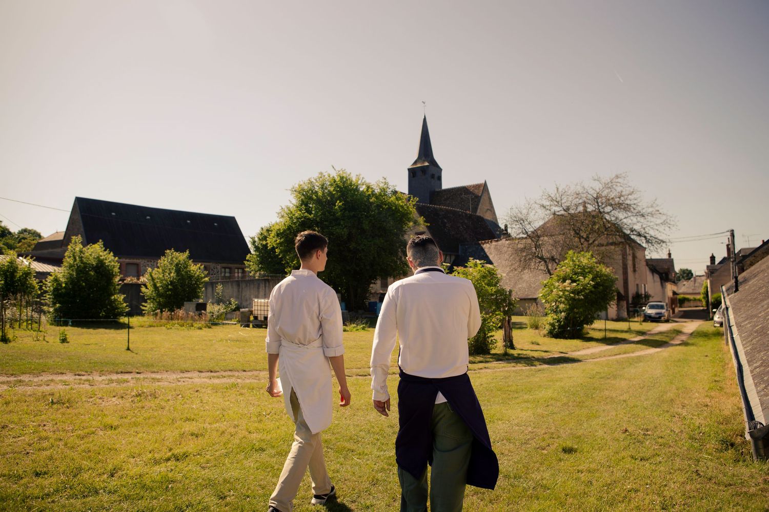 Personnes marchant dans un paysage de verdure avec un village et un clocher d'église