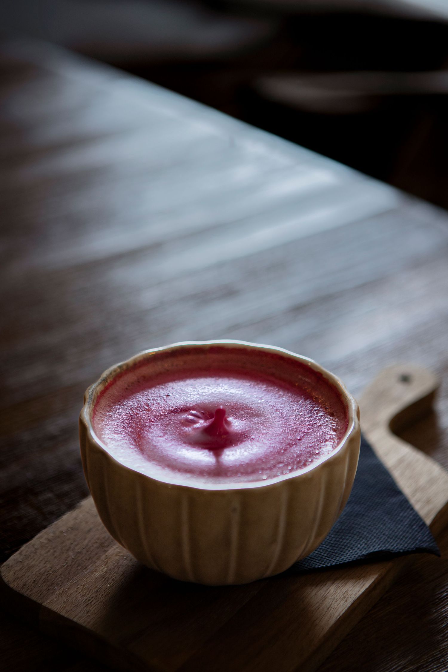 Un pink latte servie dans un bol en céramique cannelé sur une surface en bois.