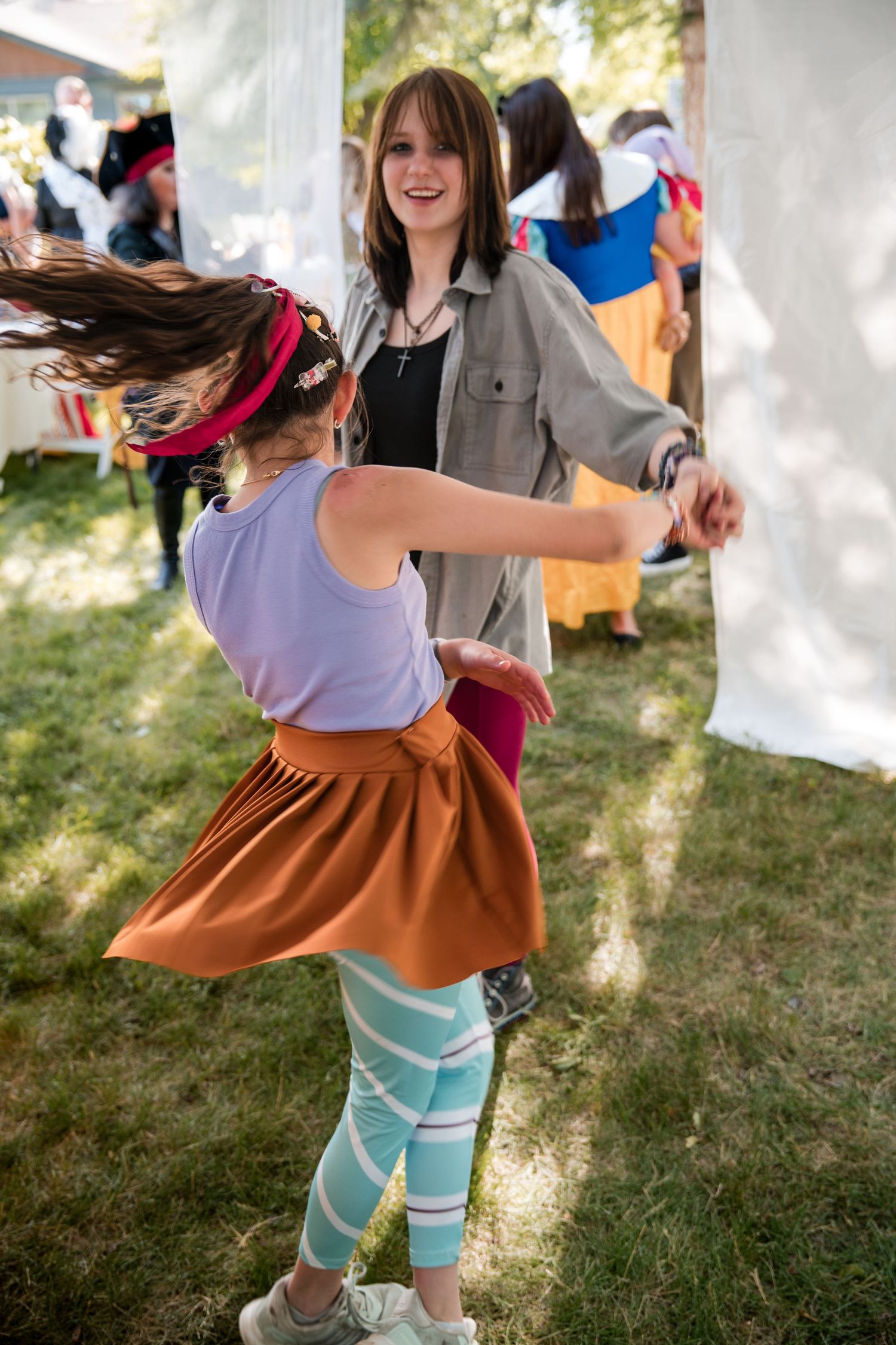 Two people dance together at a wedding, with one wearing a light blue skirt and orange dress.
