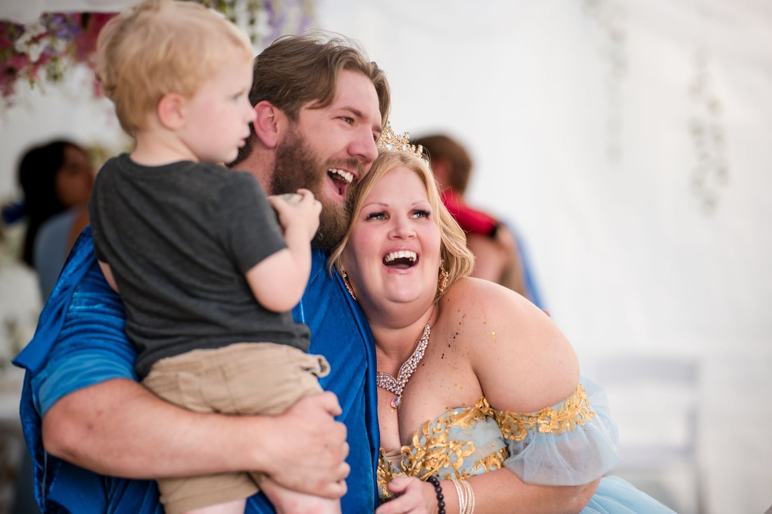 A candid moment of joyful laughter at a celebration shows people in casual and formal attire embracing.