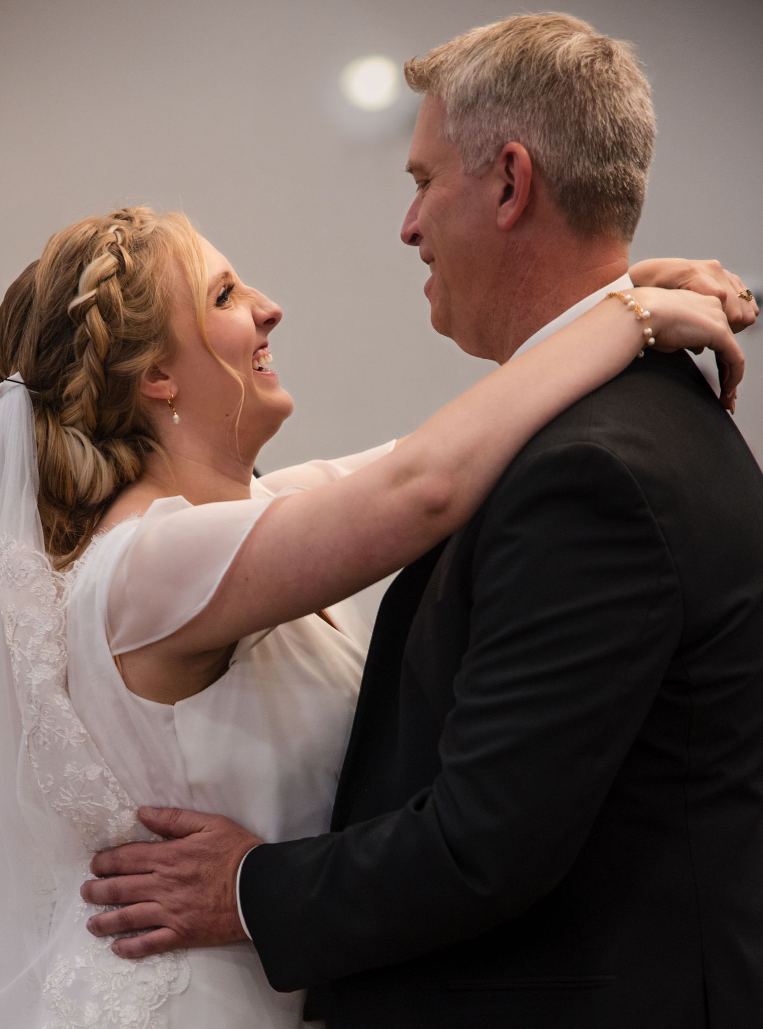 Couple embraces during their wedding dance, sharing a joyful moment with laughter and loving expressions.