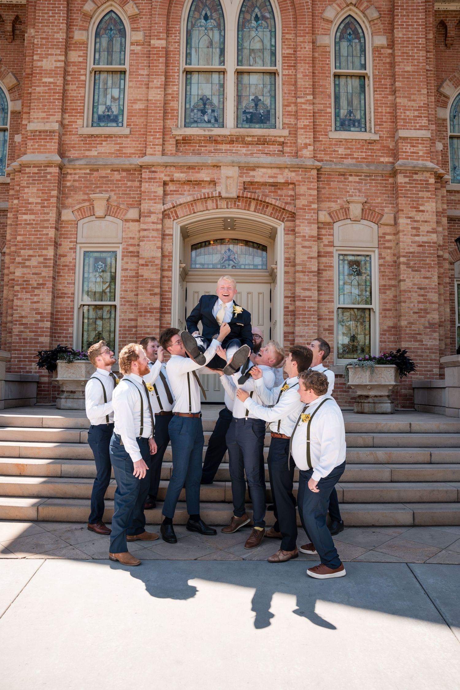 Groomsmen share a candid moment following the ceremony on the Provo City Center LDS temple steps.