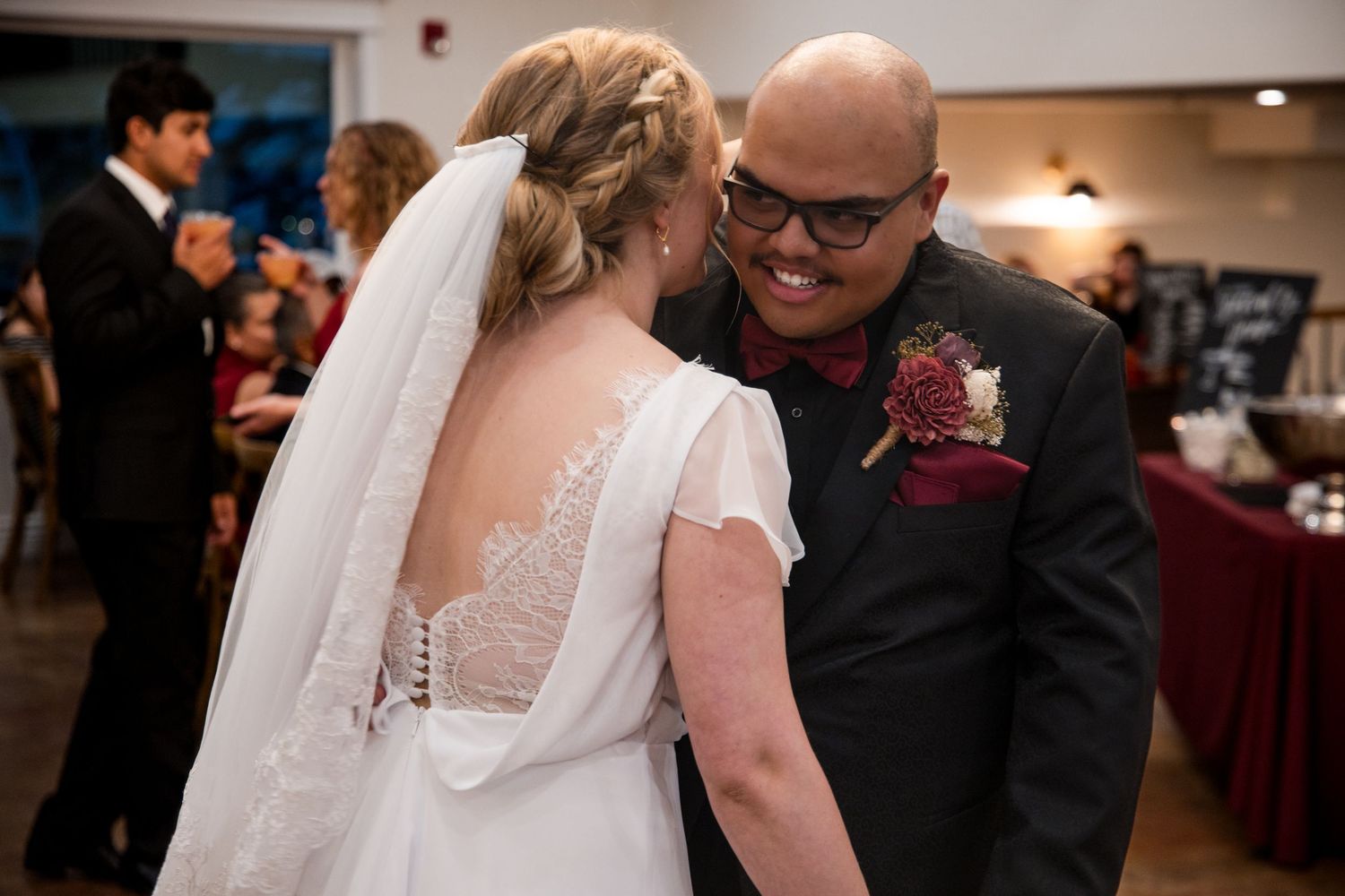 A couple dances lovingly in a dimly lit ballroom at their wedding reception.