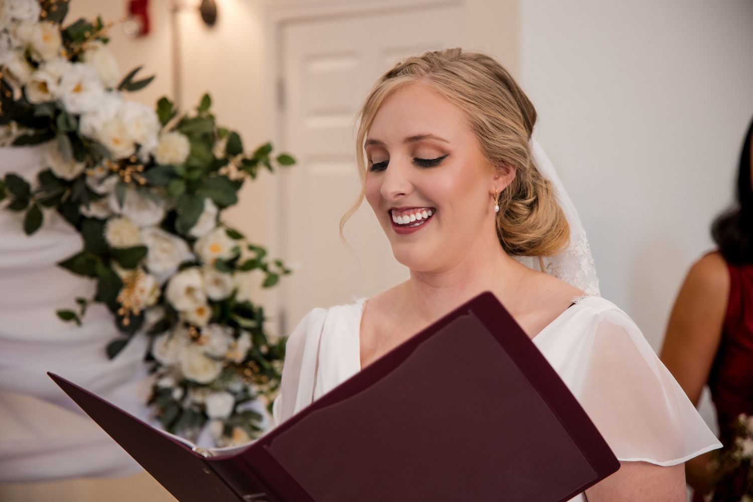 A joyful moment captured during a wedding ceremony with white floral decorations in the background.
