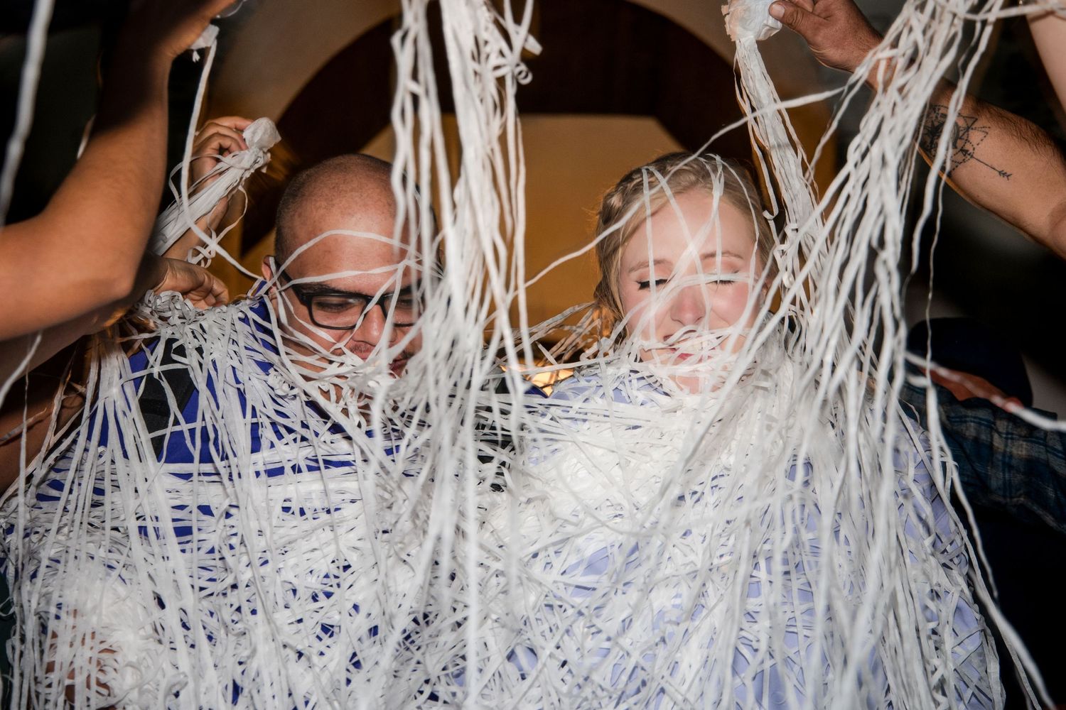 Young girl in a white dress getting covered in silly string during a playful celebration moment.