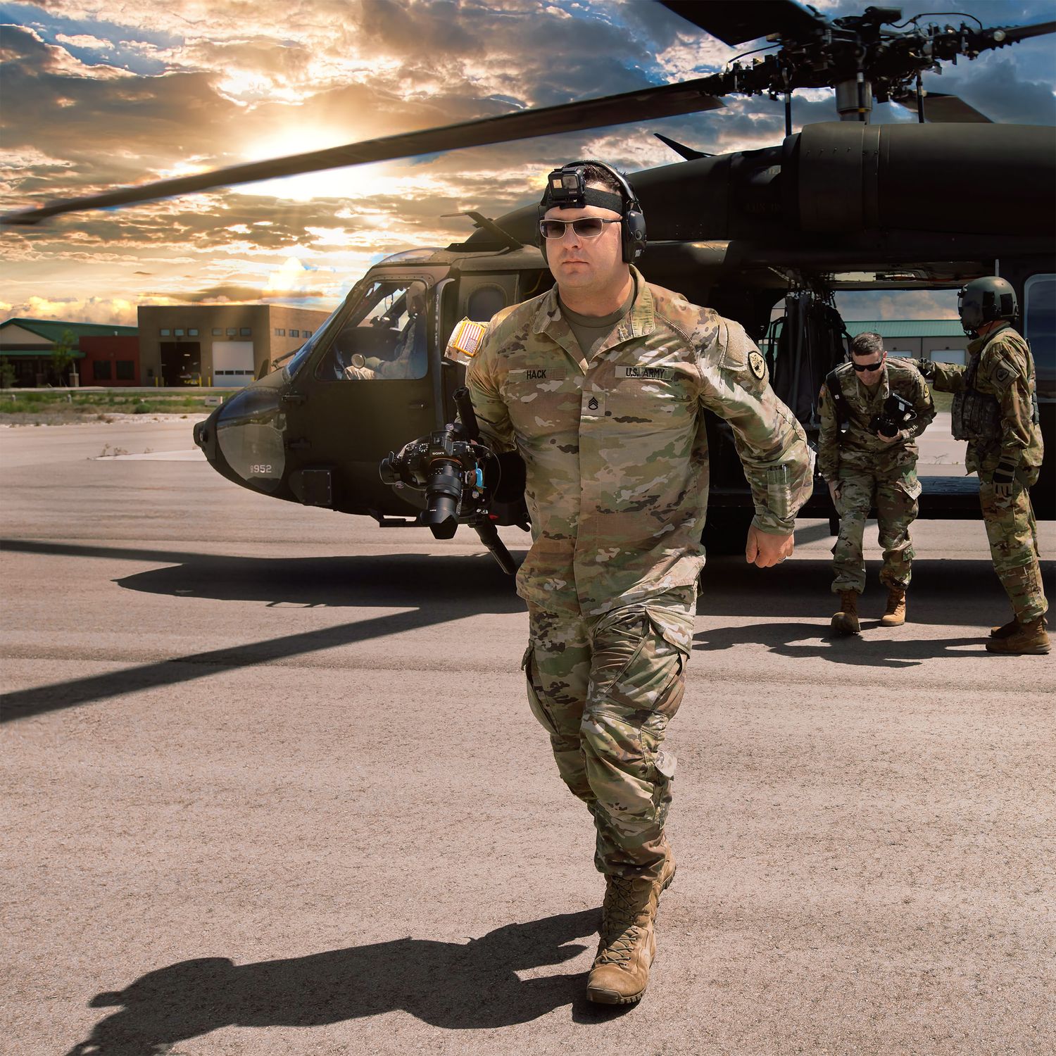 Military helicopter crew prepares for mission during dramatic sunset at airfield with multiple aircraft lined up.