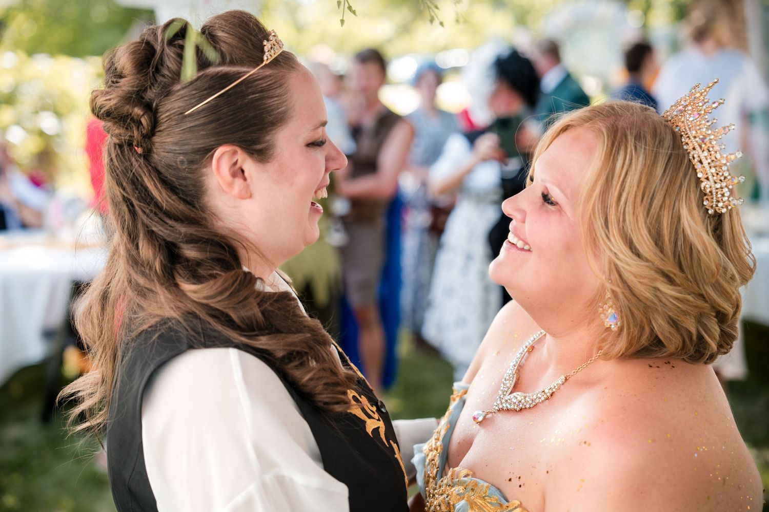 Two brides share a joyful laughing moment together during their wedding.