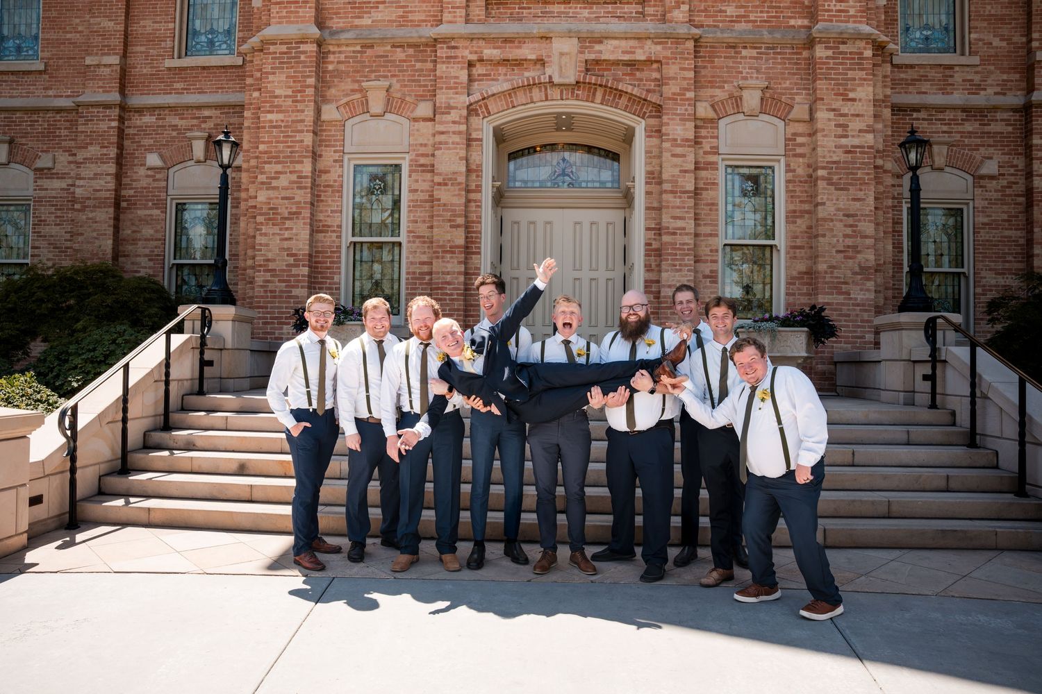 Groomsmen share a candid moment following the ceremony on the Provo City Center LDS temple steps.
