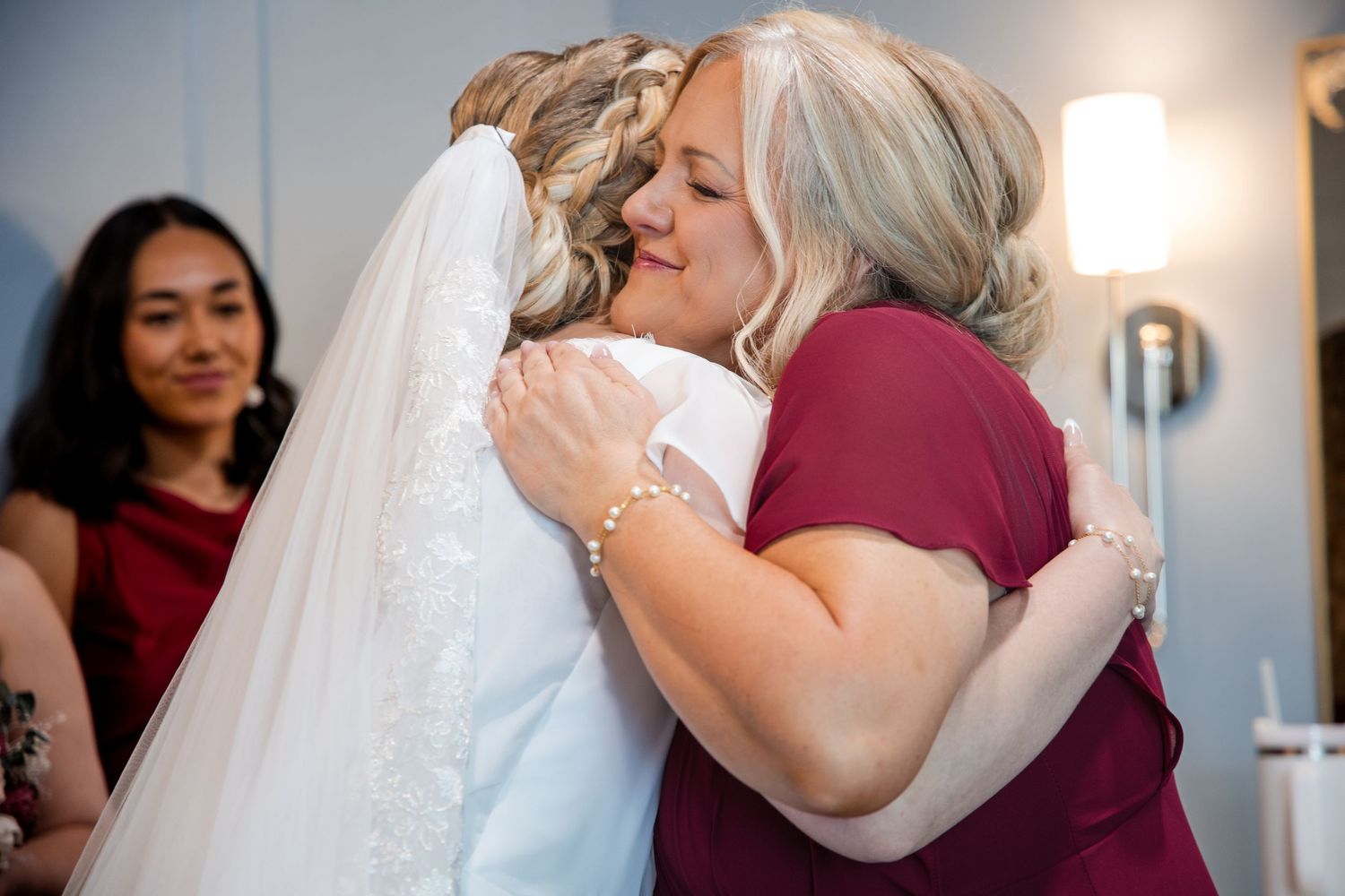 A tearful embrace between mother and daughter in formal attire during an emotional moment at a wedding.