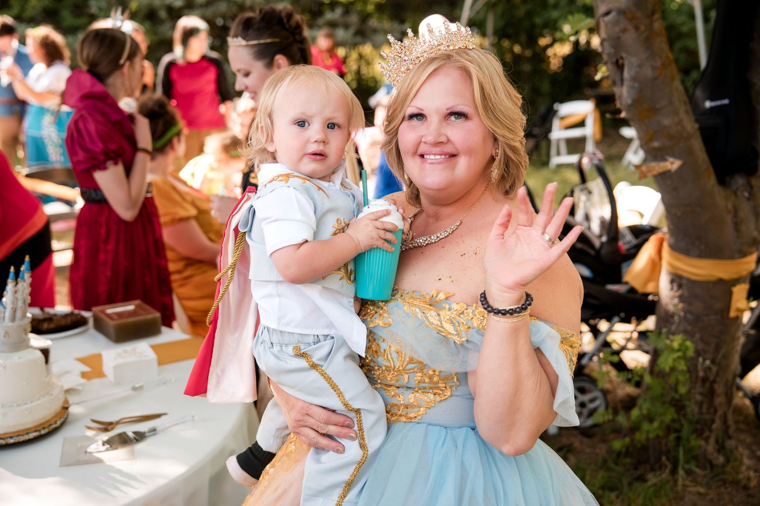 A cheerful moment at a wedding shows a bride in a blue dress holding a small child at a party gathering.