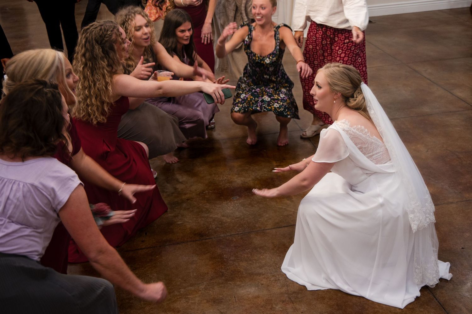 Wedding guests enjoy dancing together on a wooden dance floor during a reception celebration.