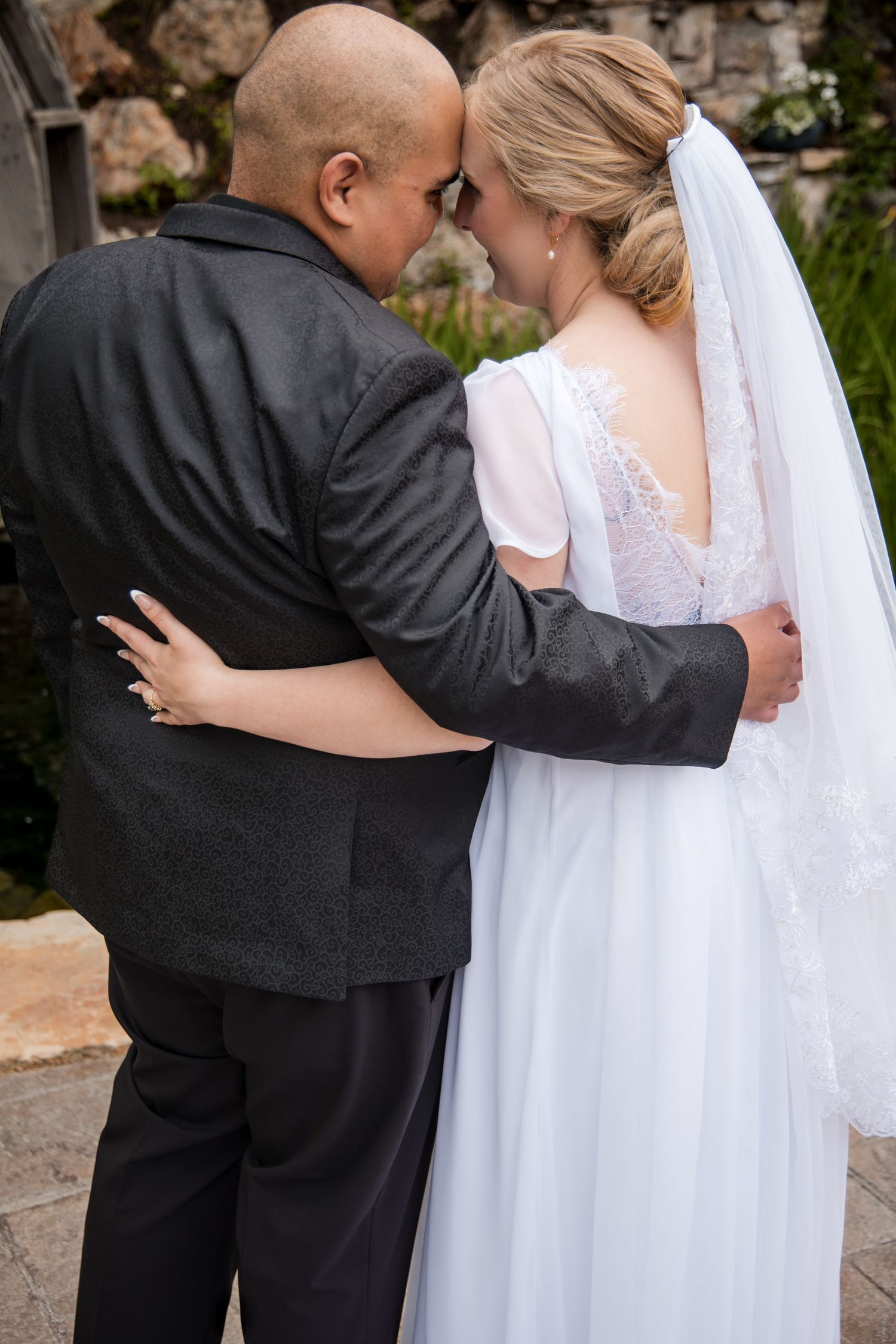 Three sequential photos show a tender embrace between a couple at a wedding, with the bride in white and groom in black.