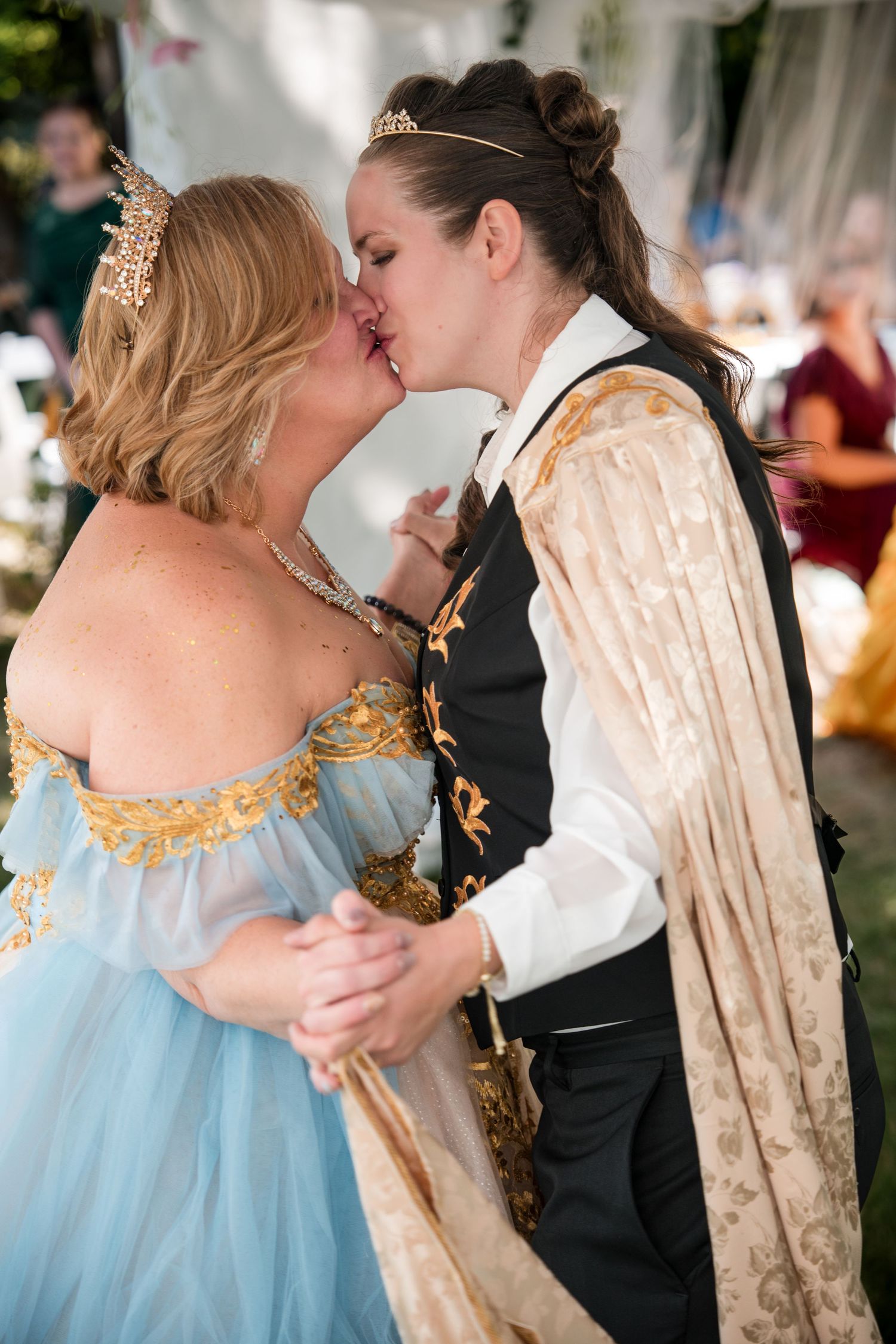 A wedding couple in formal attire dances together, with the person in a light blue dress and their partner in black and white.