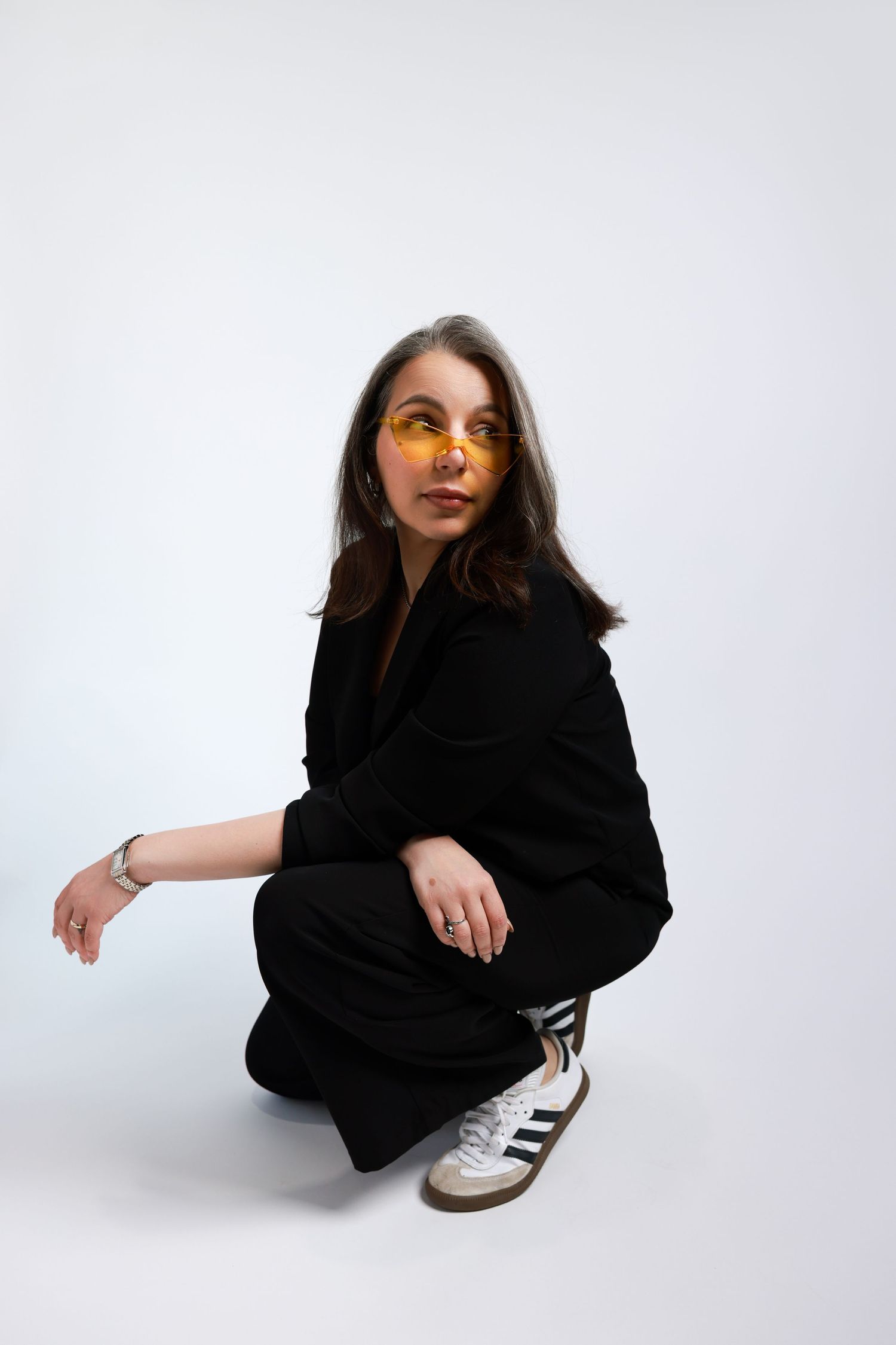 Editorial style fashion poses showing a person in black attire sitting against a white background.
