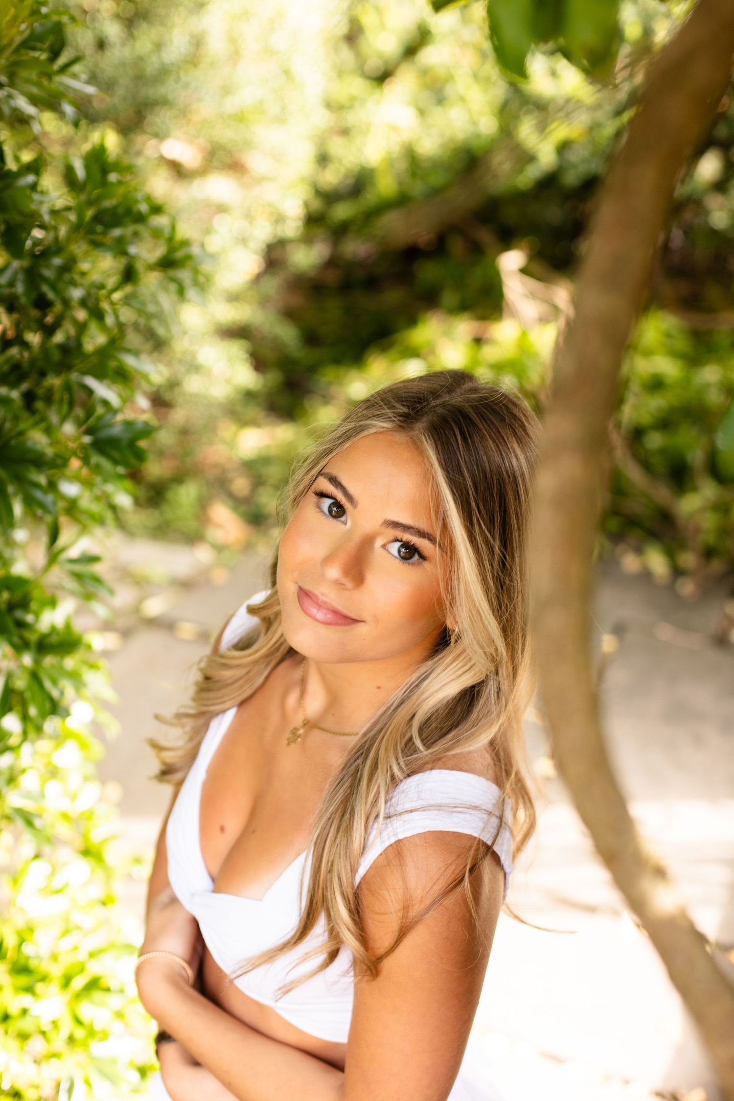 Outdoor portrait photoshoot with soft natural lighting and green foliage in the background.