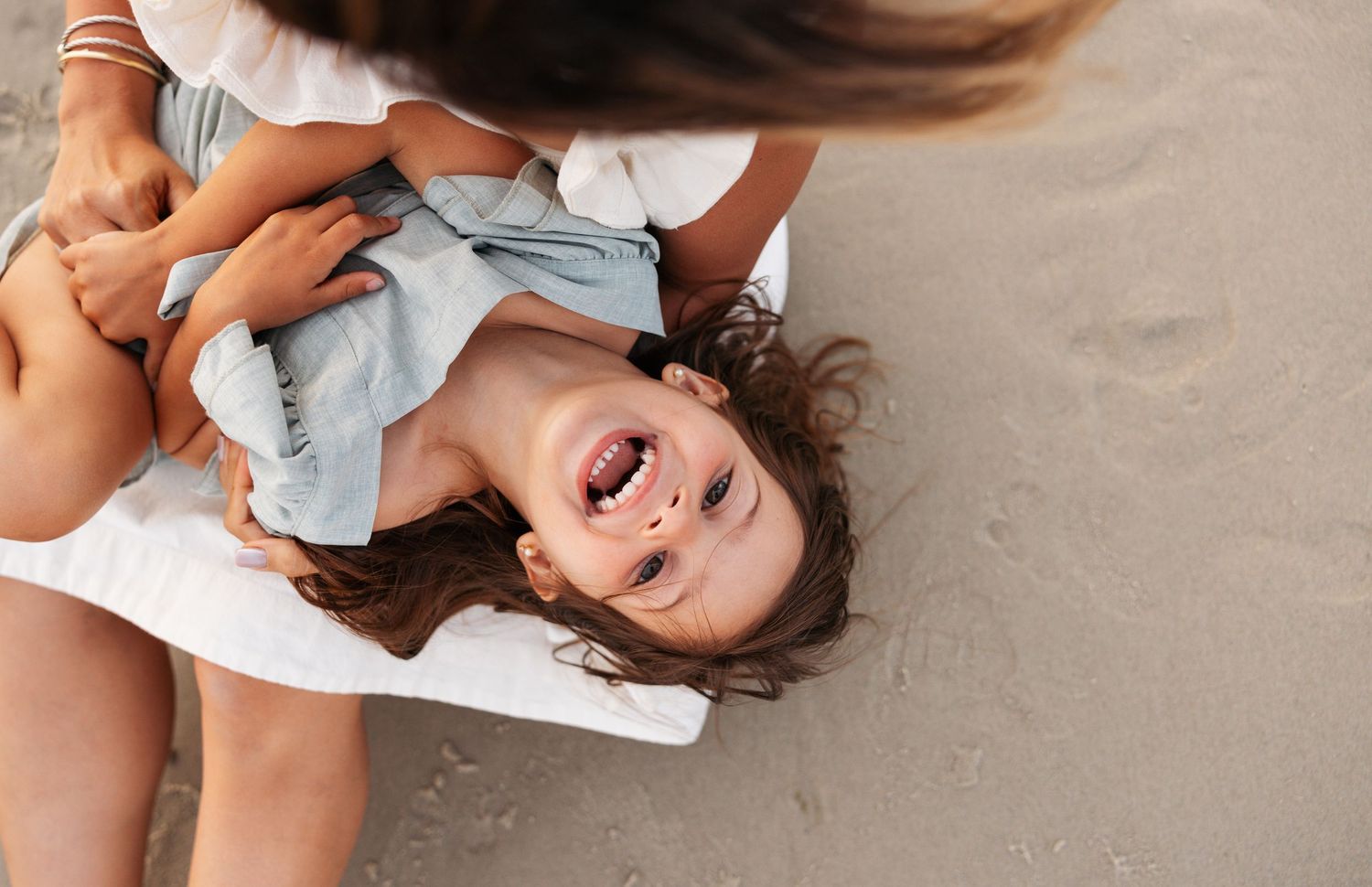 Joyful moments captured in a sequence of beach photos with white attire and playful poses in the sand.