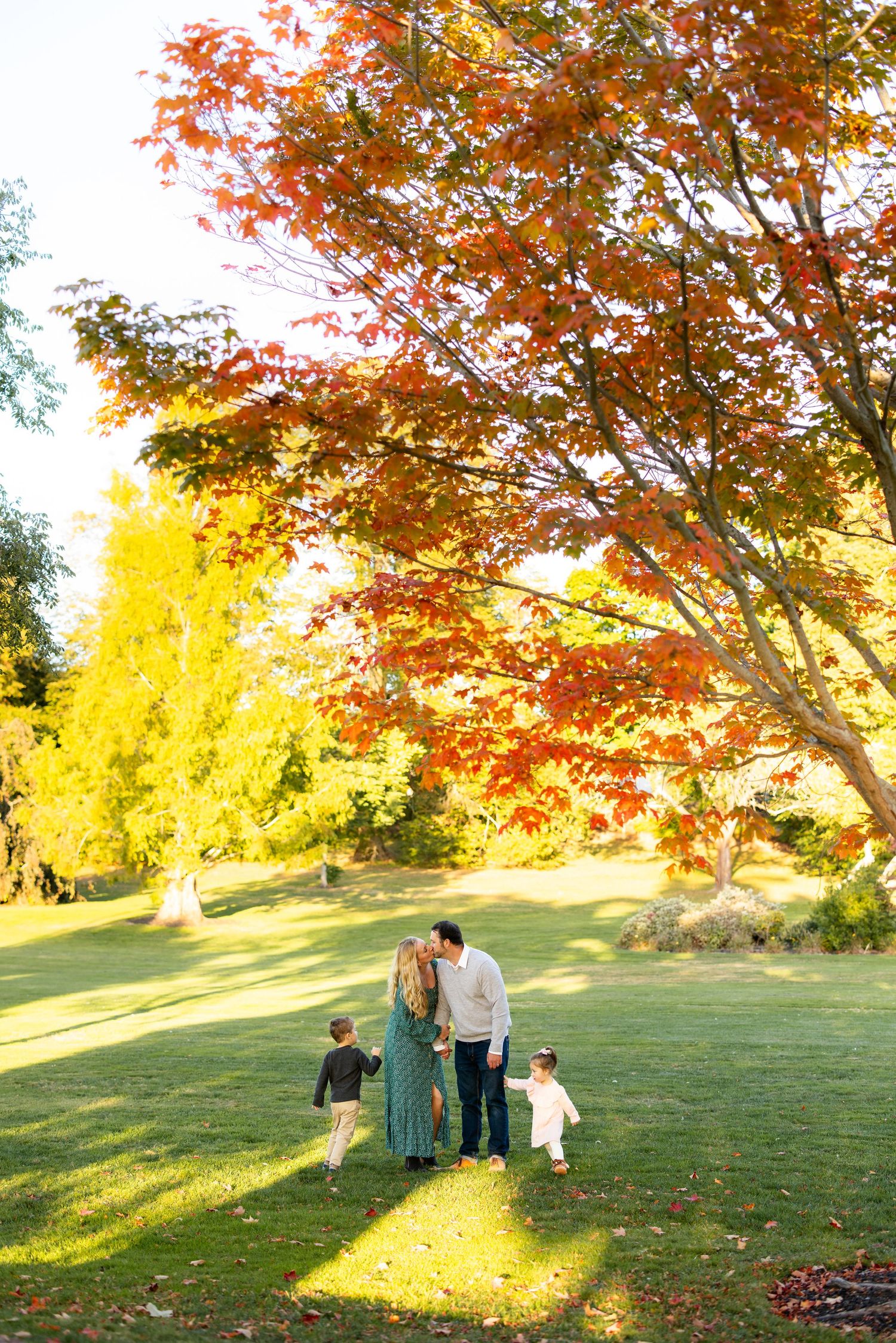Family enjoys autumn day under vibrant red and yellow maple trees.