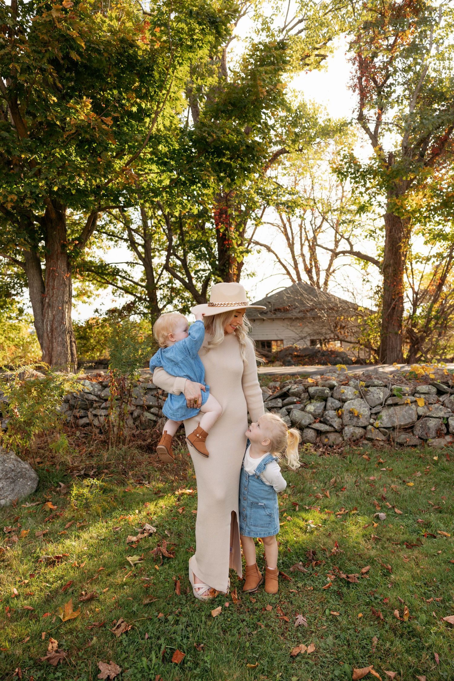 A series of candid fall photos showing playful moments against a stone wall and autumn trees.
