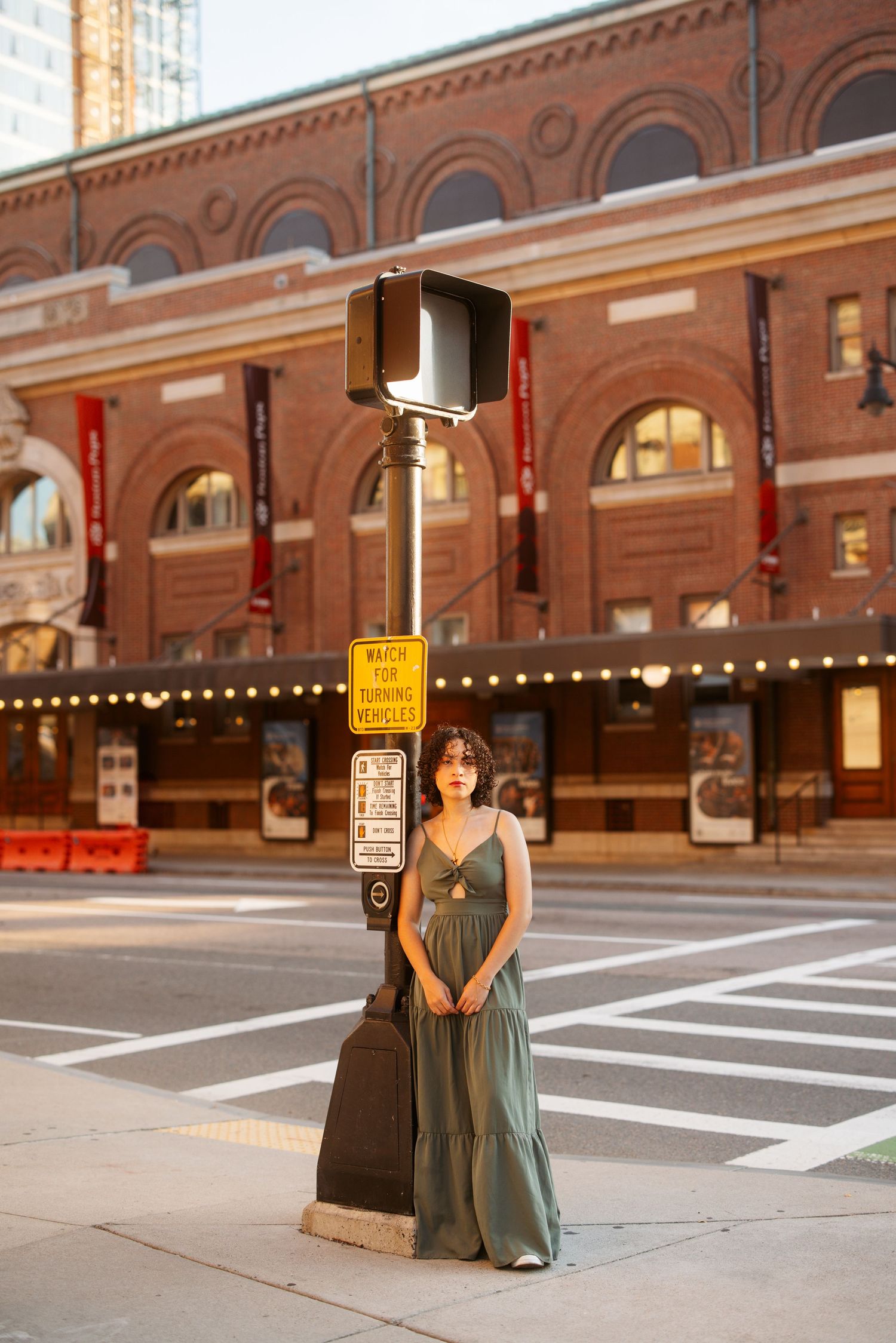 A couple poses for engagement photos in front of a historic brick building at sunset.